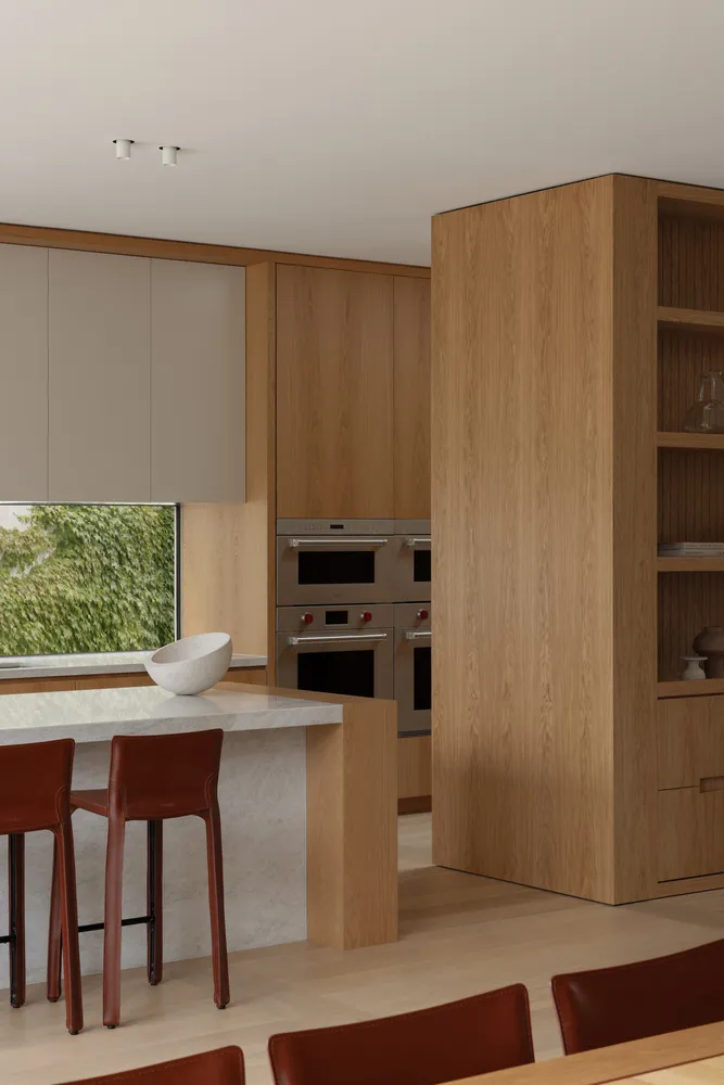 Modern kitchen with wooden cabinets, granite countertops, stainless steel appliances, and natural light from a large window
