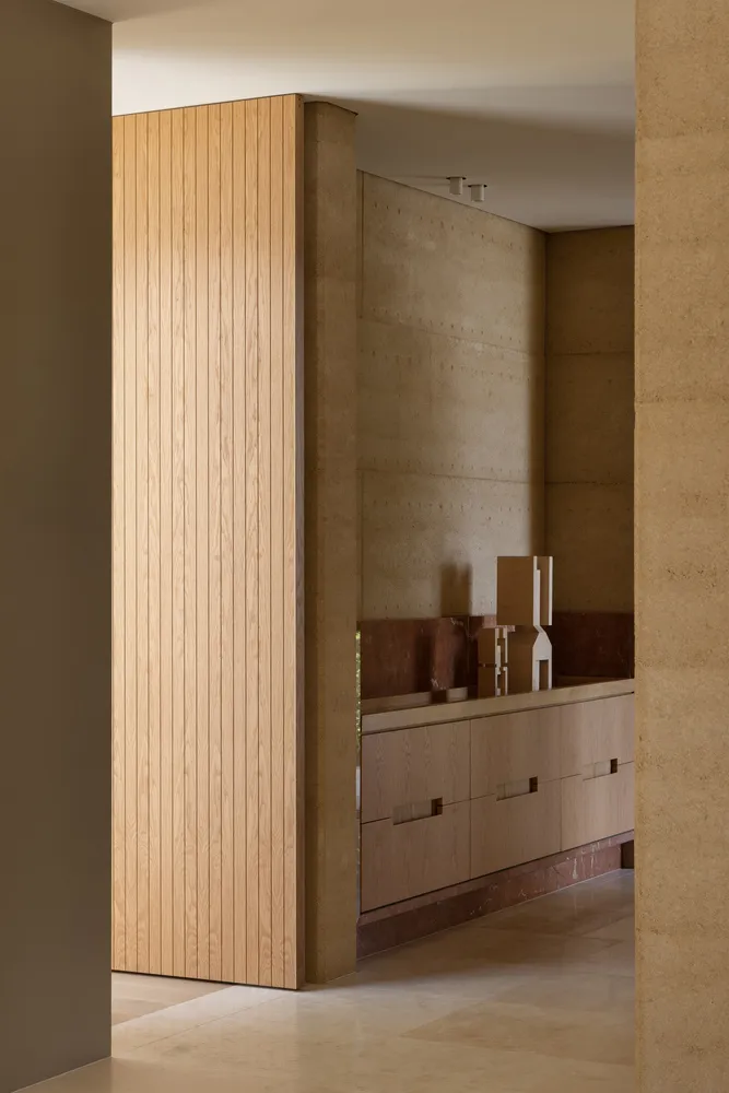 A tan-colored room with a large wooden cabinet, brown door, and two other doors, featuring a sink and a functional space