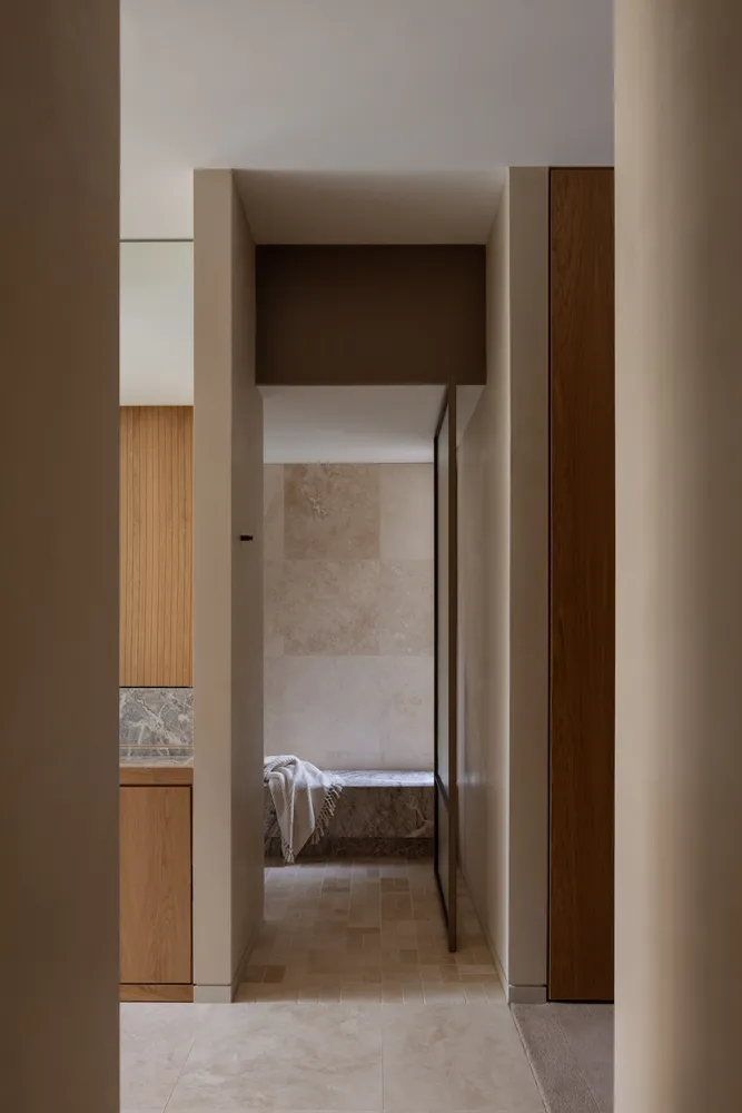 A warm and inviting hallway with wooden features, white walls, and two doorways leading to adjacent rooms