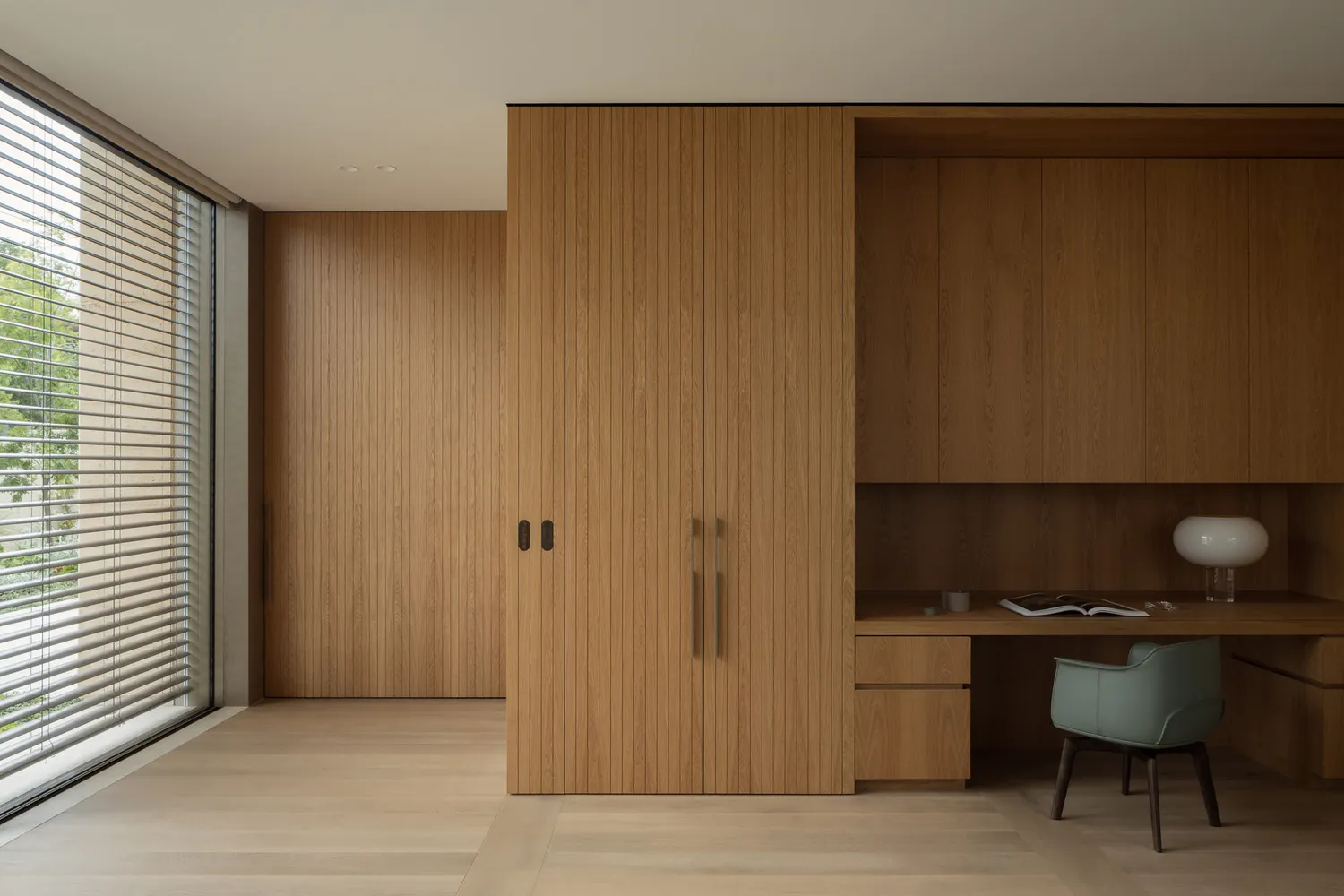 A warm and inviting bedroom with a wooden cabinet, desk, chair, and scattered books, creating a comfortable study area