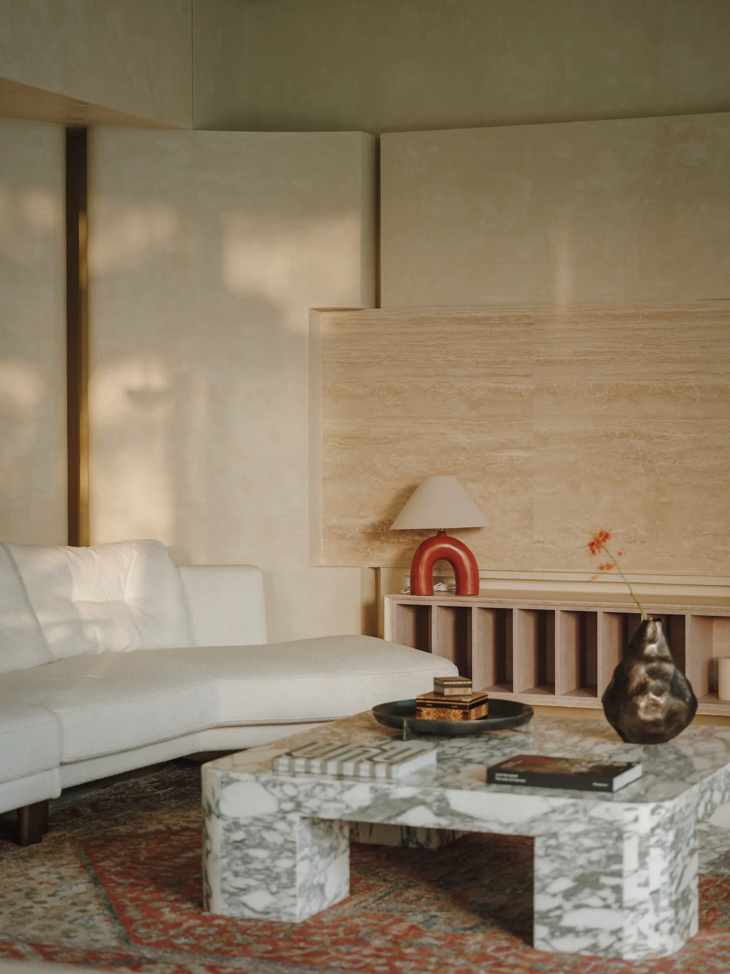 Cozy modern living space with a white couch, coffee table, books, vases, and potted plants, in a clean and inviting atmosphere