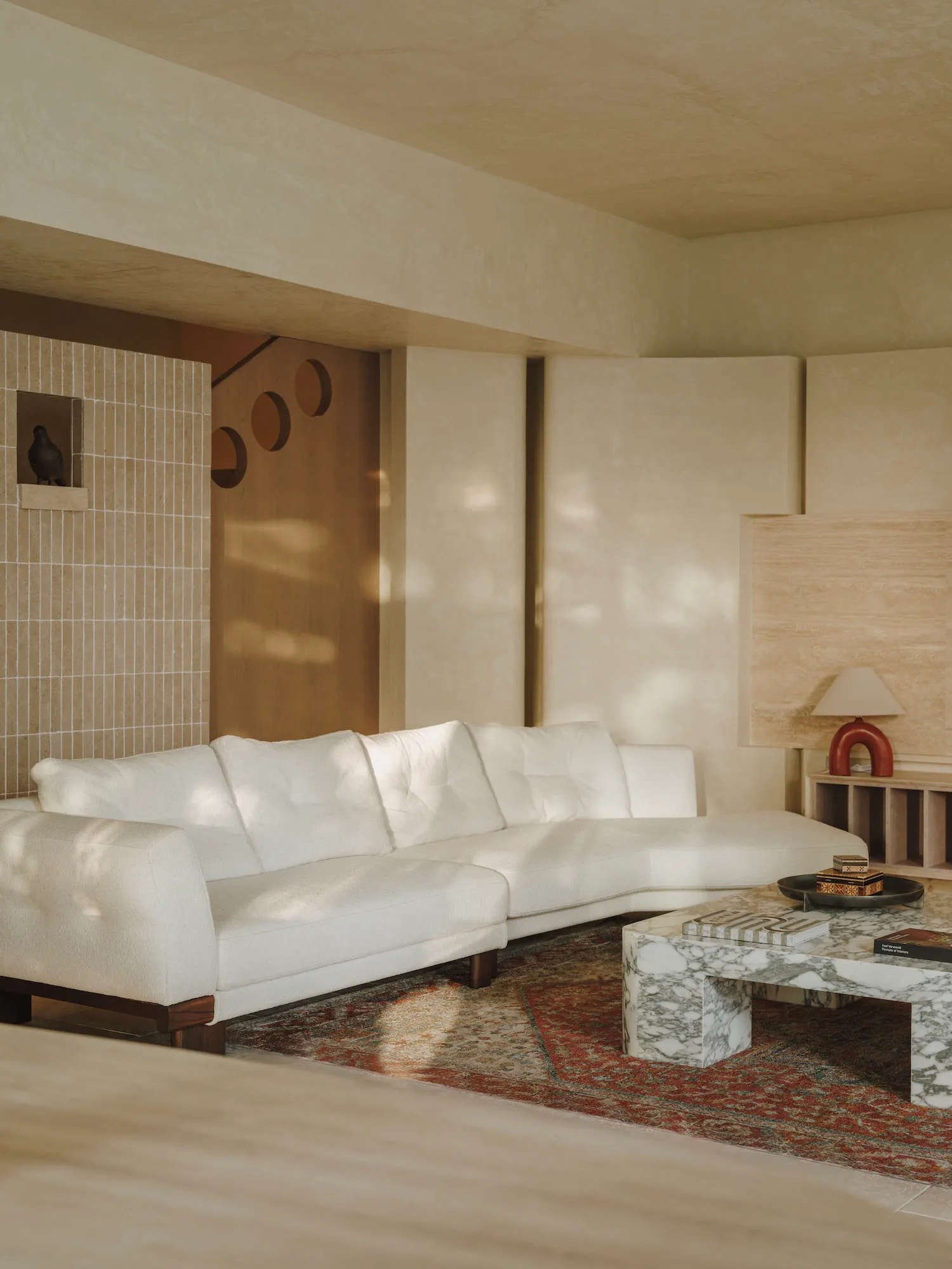 Bright and inviting living area with white couches, a coffee table, and sunlight streaming through the windows