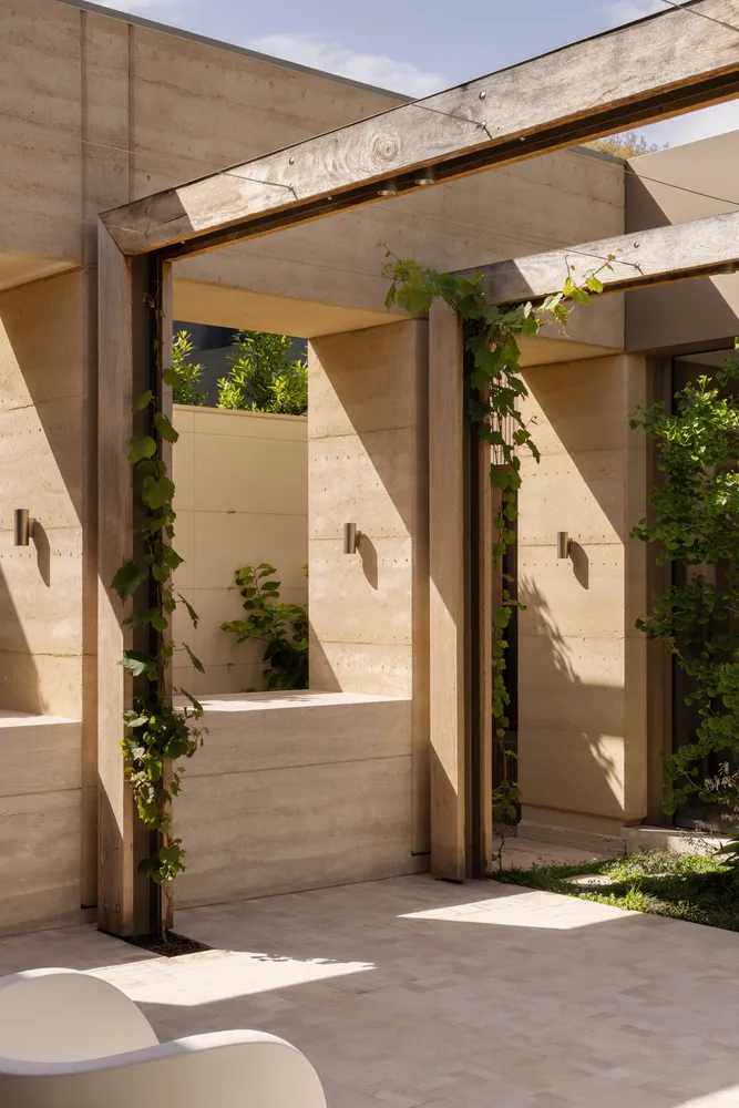 A modern building with a concrete exterior, featuring several windows, two archways, and natural light from the daytime sun