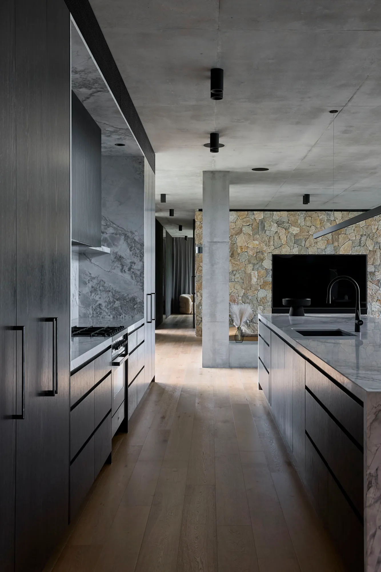 Open modern living space with a kitchen island, wooden flooring, a couch, TV, and dining table