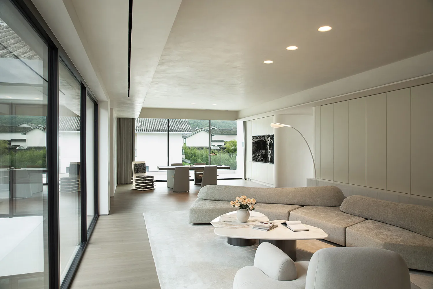 A bright and inviting living area with a couch, chairs, dining table, and decorative vase, surrounded by natural light from a window