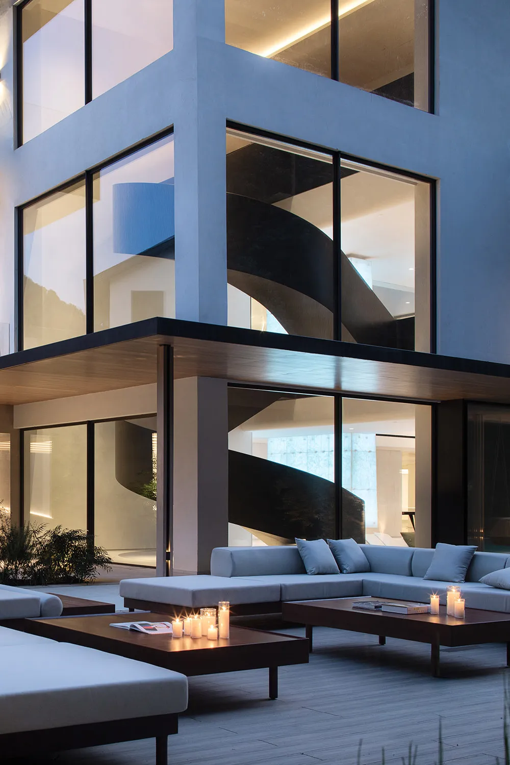 Modern living space with white walls, multiple windows, a couch, chair, and dining table, featuring clean lines and minimalistic design