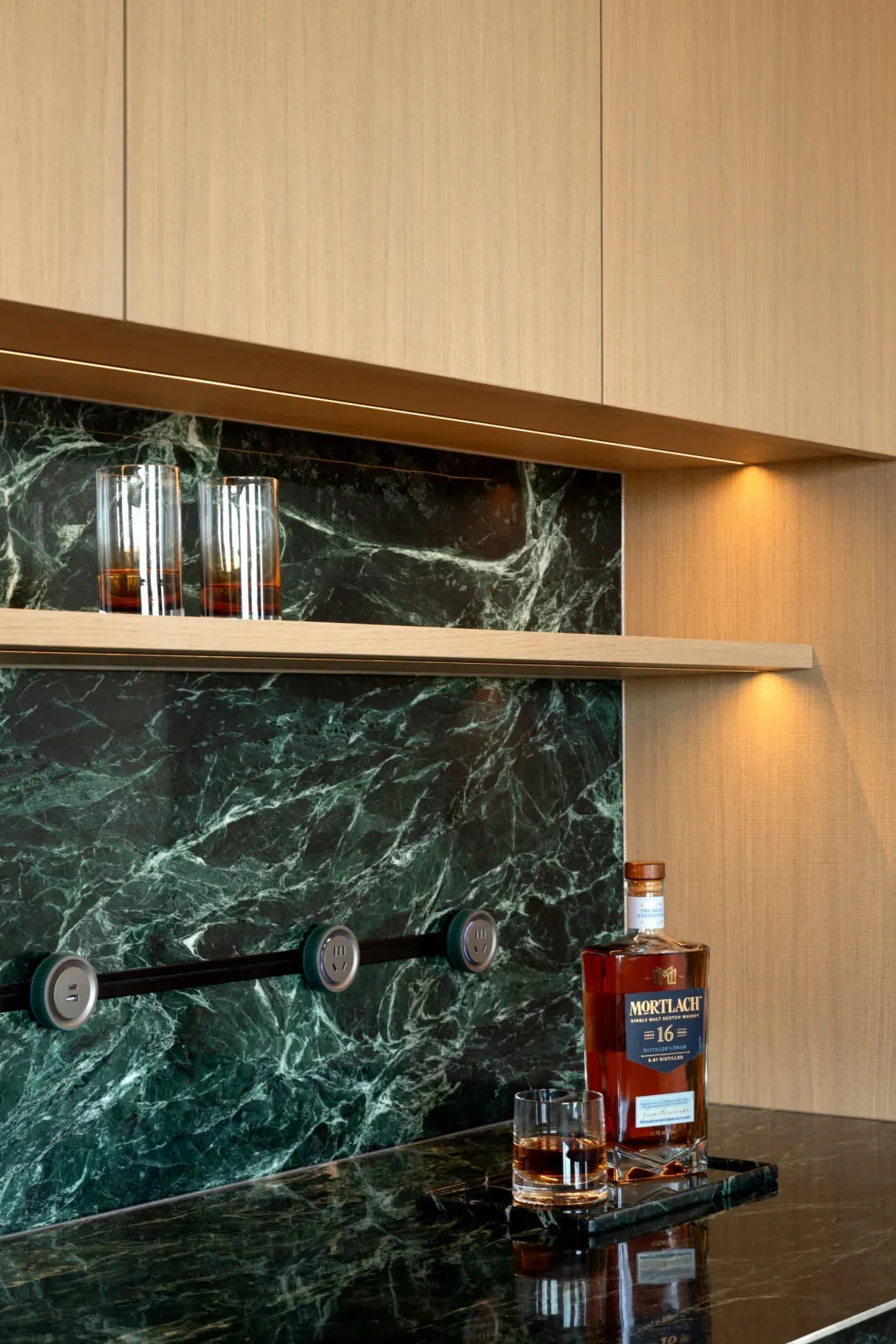 A kitchen with a marble countertop, whiskey bottle, and two wine glasses, creating an elegant and sophisticated atmosphere