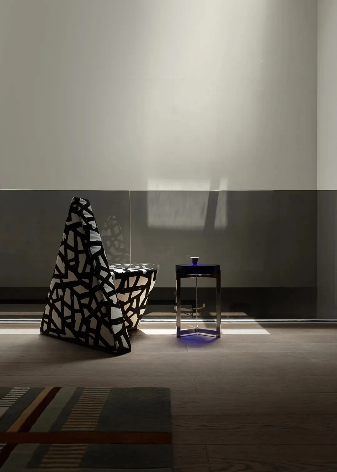Dimly lit living room with a black and white chair, two tables, and a cozy atmosphere