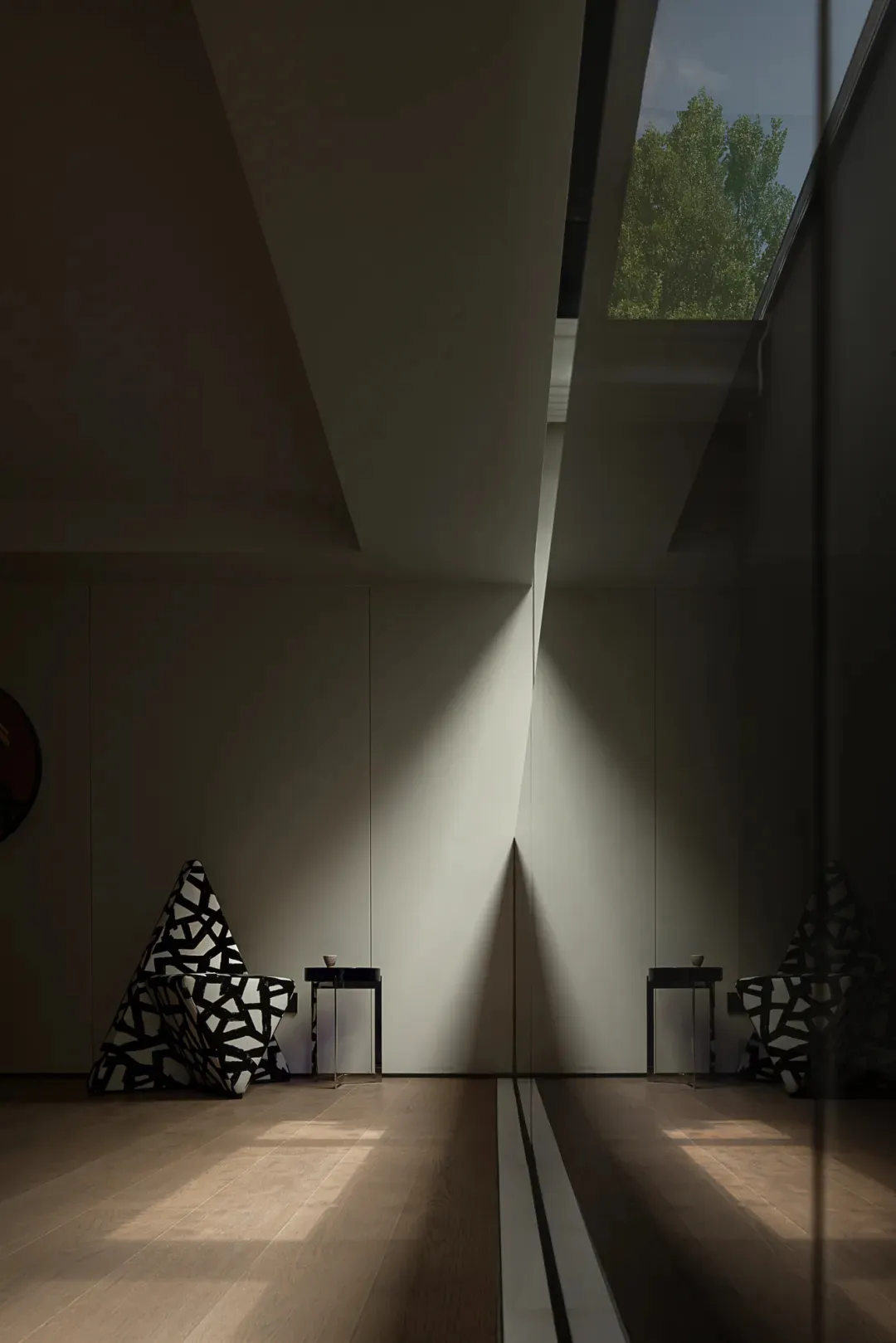 A modern minimalist living area with a large white wall reflecting sunlight, two chairs, and a dining table