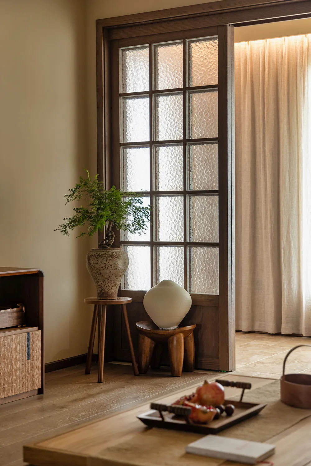 Cozy living space with a doorway, potted plants, and a vase, featuring a warm and inviting atmosphere