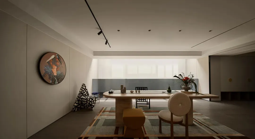 Empty living room with a large window, two chairs, a dining table, and vases and bowls, flooded with natural light