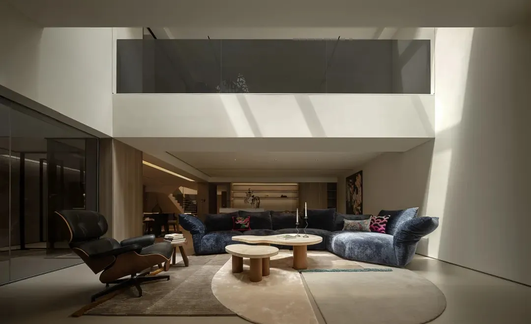 A modern living area with a couch, dining table, chair, and potted plant, well lit with natural sunlight or artificial lighting
