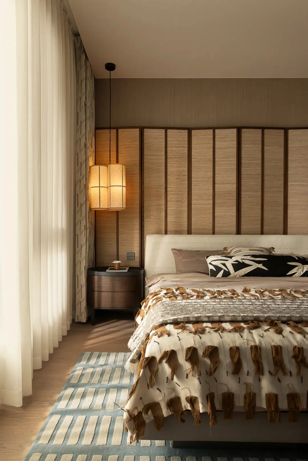 A cozy bedroom with a large bed, brown blanket, and wooden floor, creating a warm and inviting atmosphere