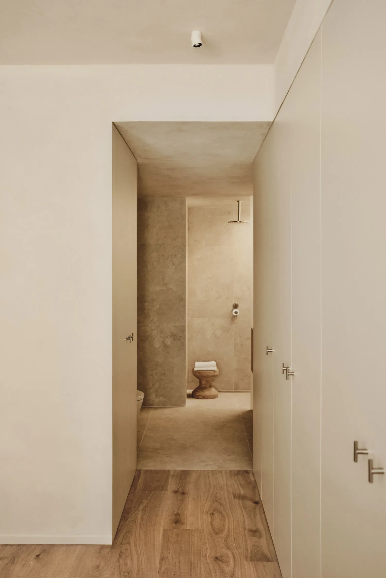 Bathroom with tile walls, a toilet, and two doors, creating a calm and inviting atmosphere