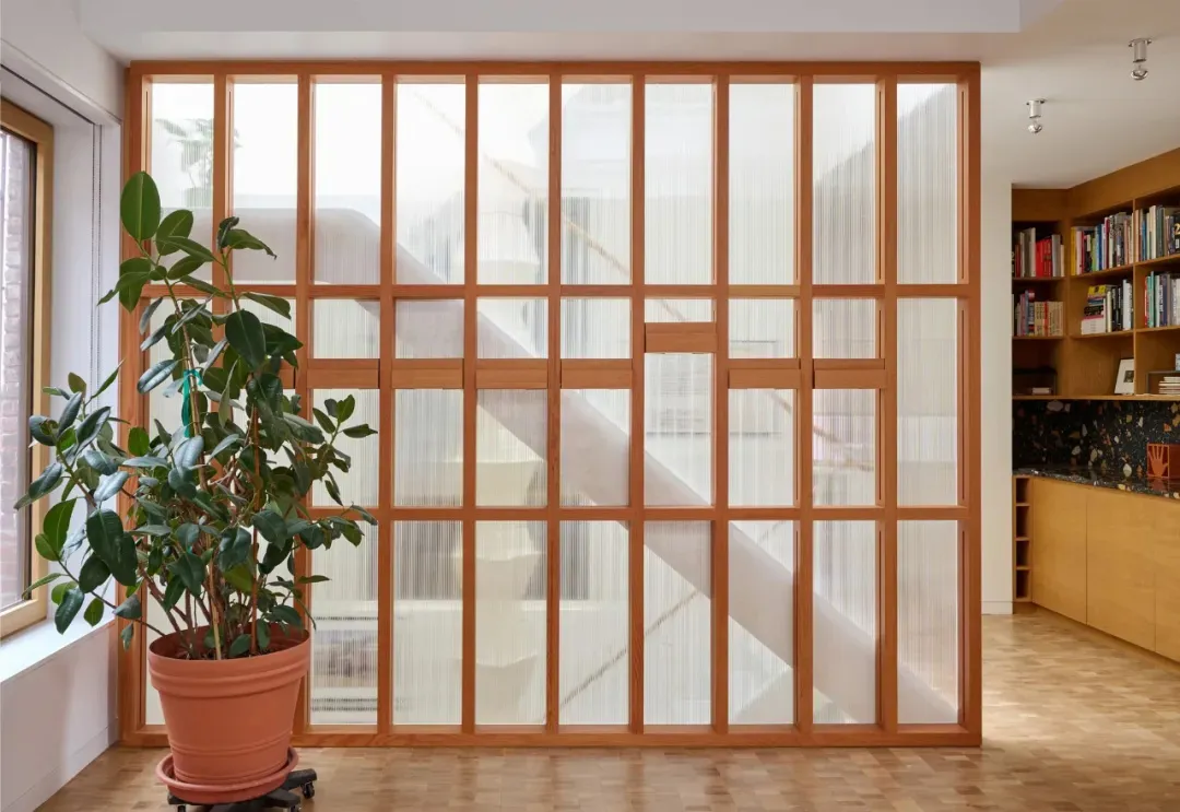 A well-lit home office with wooden blinds, two potted plants, and a calm atmosphere
