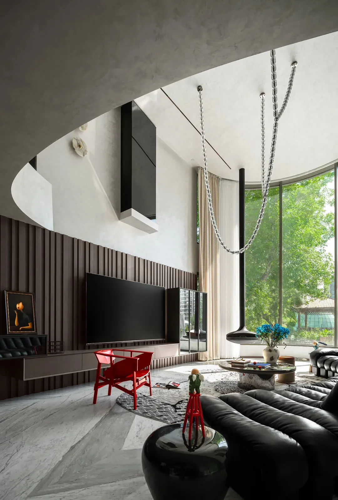 Sleek modern living space with a flat screen TV, a couch, a chair, and potted plants, featuring openness and functionality