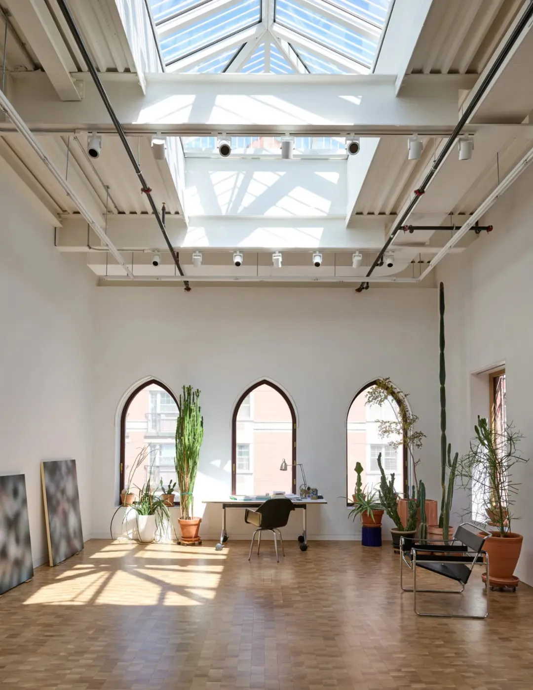 Open living area with a skylight, potted plants, chairs, and a desk, featuring a bright and inviting atmosphere with a focus on functionality and comfort