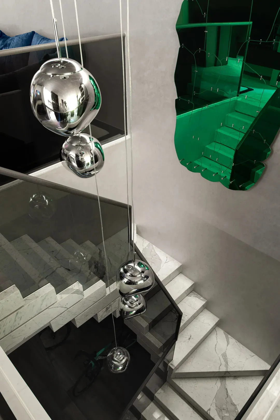 A luxurious staircase with marble steps and a unique installation featuring three large glass or crystal orbs hanging from the ceiling