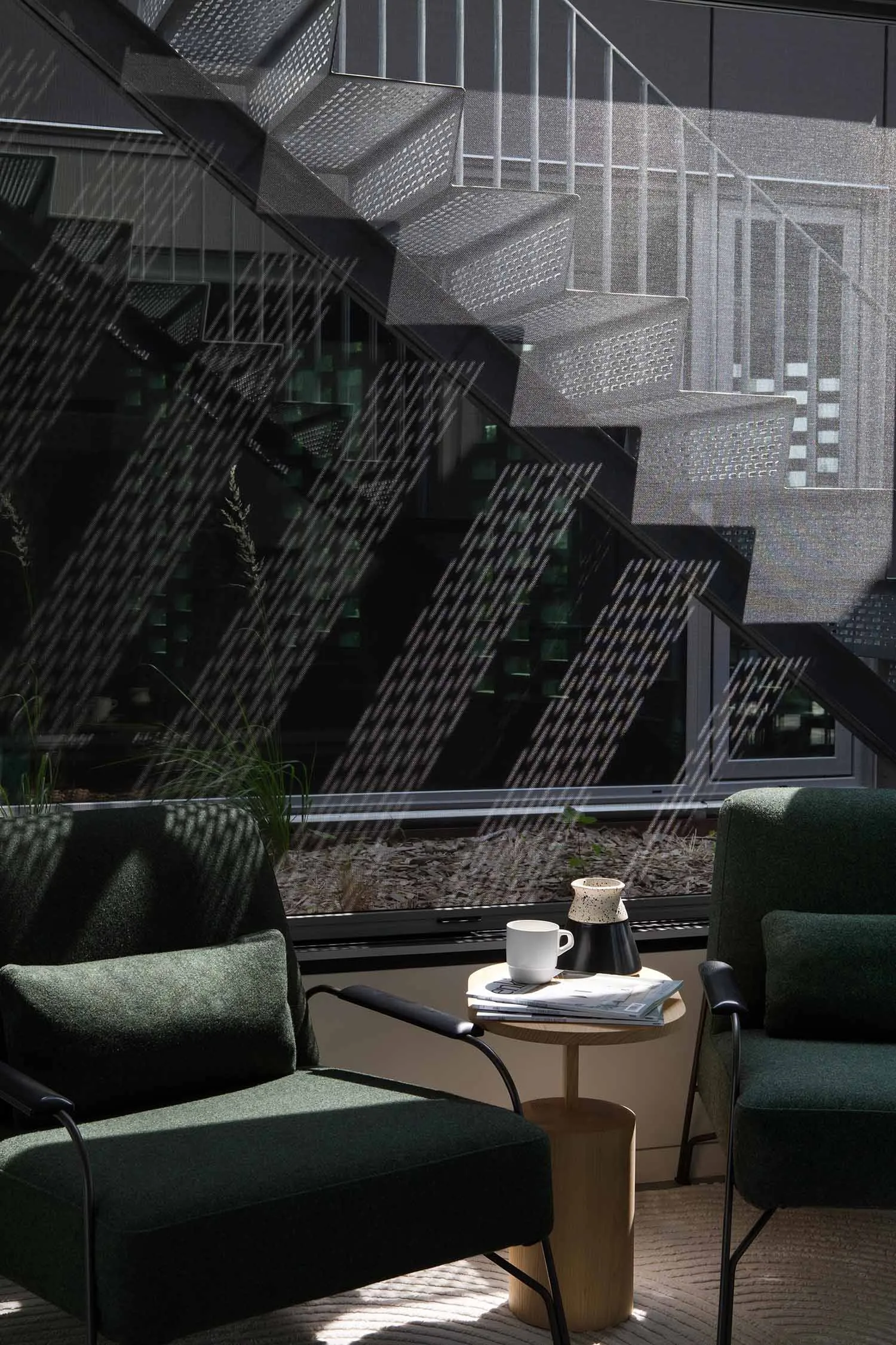 A wooden staircase with a metal railing, a chair, and a coffee cup on a nearby table in a calm and inviting atmosphere