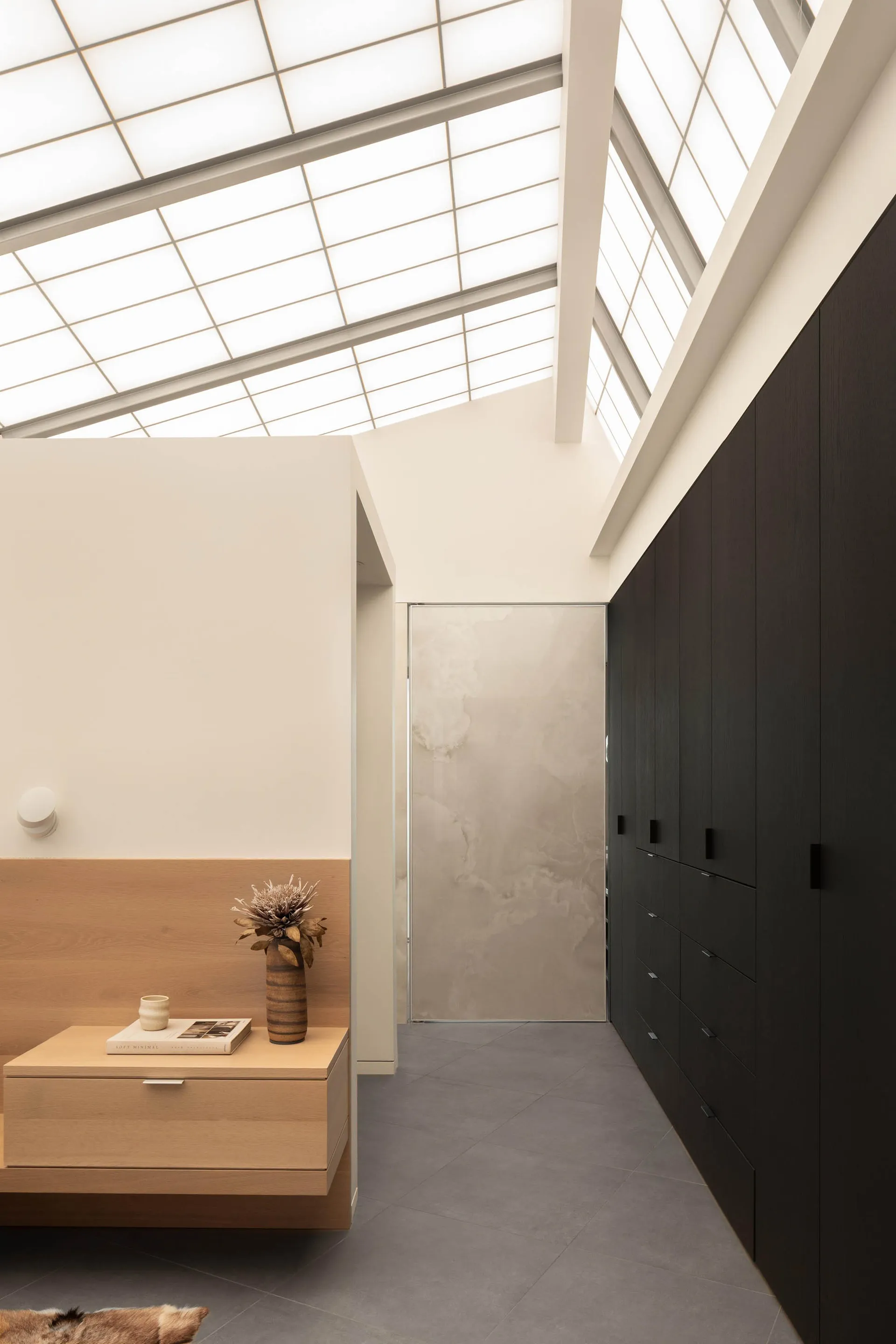 A modern study space with a wooden desk, two cabinets, and a vase on the desk, featuring a focus on functionality and simplicity