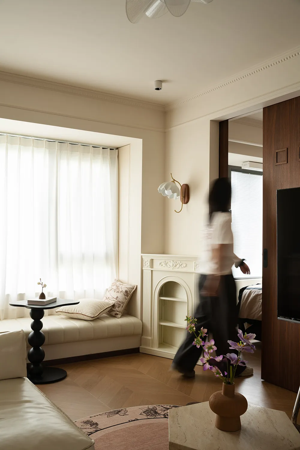 A cozy living space with two beds, a TV, a couch, a chair, a dining table, and potted plants