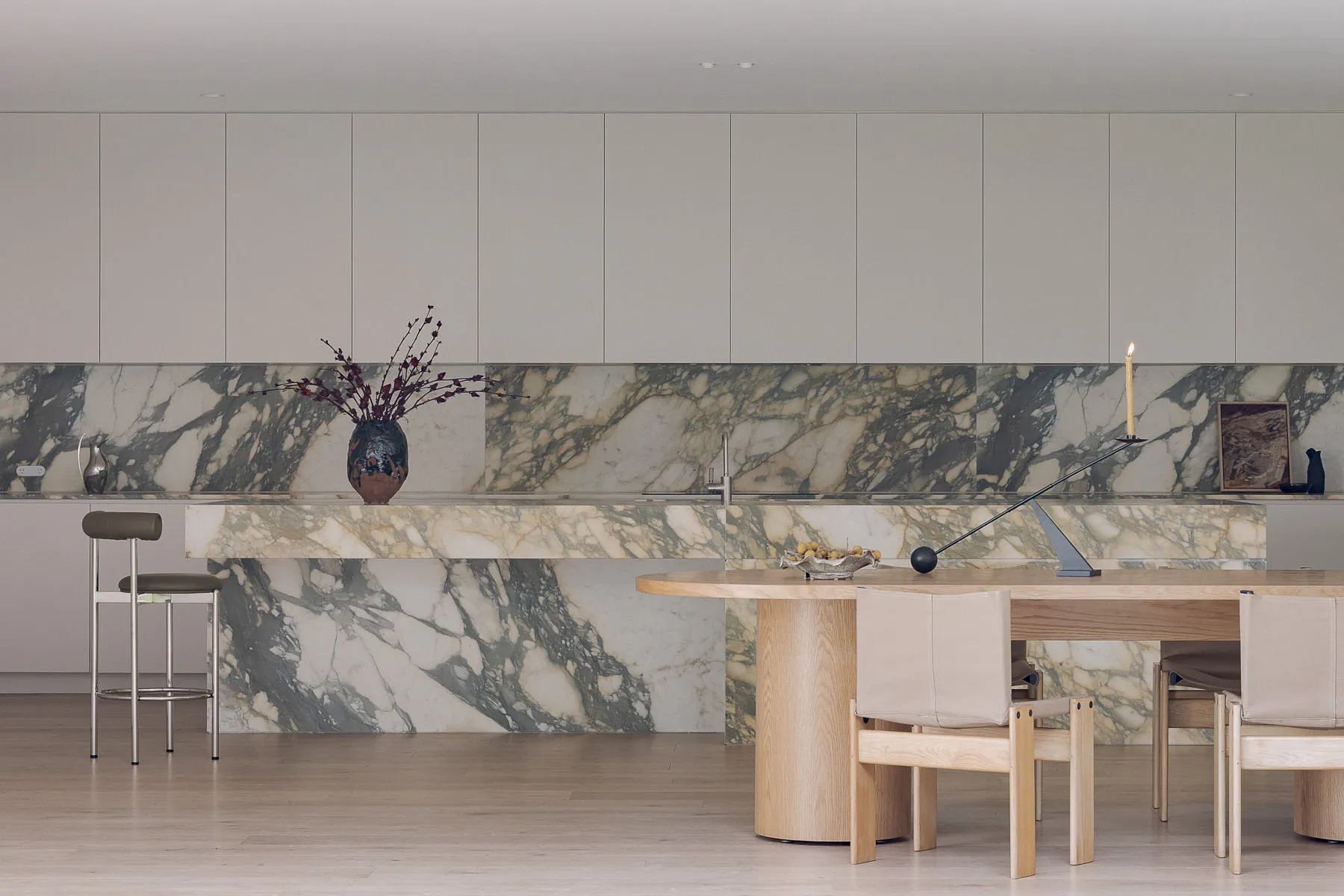 Modern kitchen with marble countertops, a wooden table, and a large island, featuring clean and organized space with a focus on functionality and aesthetics