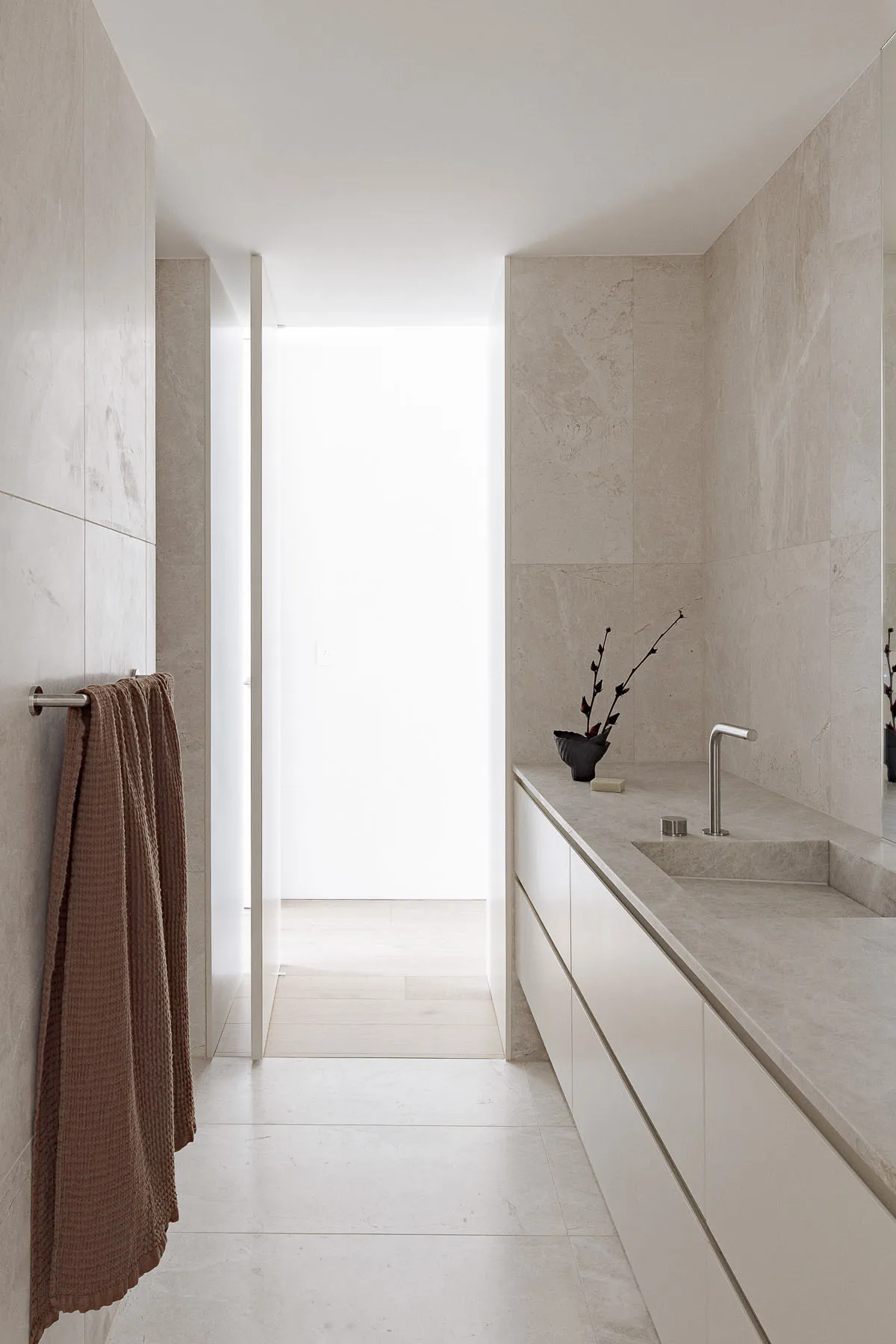Clean and modern bathroom with a sink, mirror, and towel rack, featuring white walls and minimalist decoration