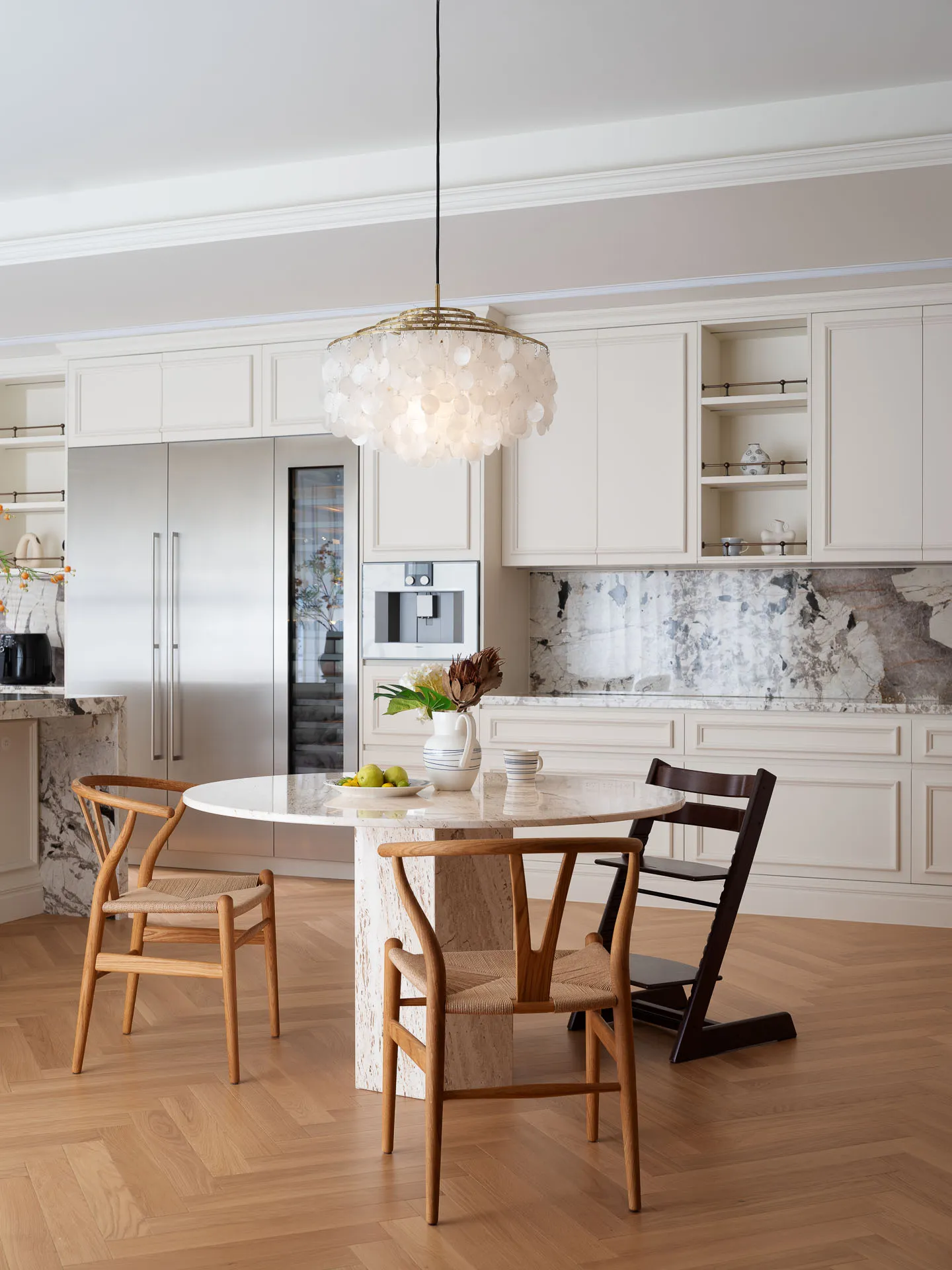Warm and inviting kitchen with wooden floors, white cabinets, and a dining table with a bowl, chairs, and kitchen appliances