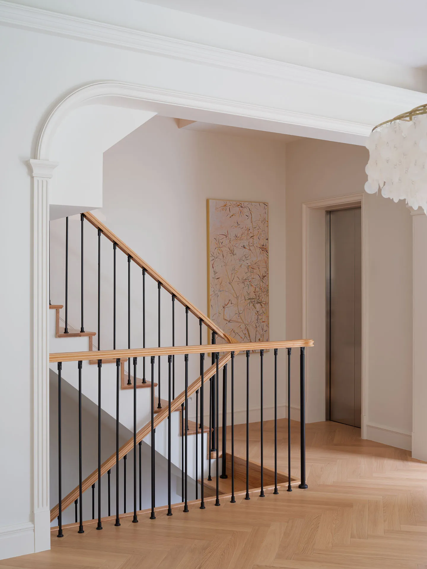 A photo of a well-designed staircase with black metal railings and white walls, featuring warm wooden steps and a sophisticated atmosphere