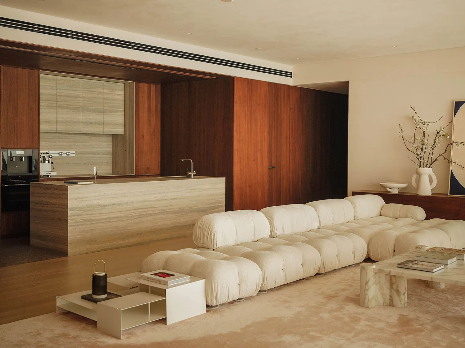 Open modern living space with a white couch, two sinks, and wooden walls, featuring clean lines and simplicity
