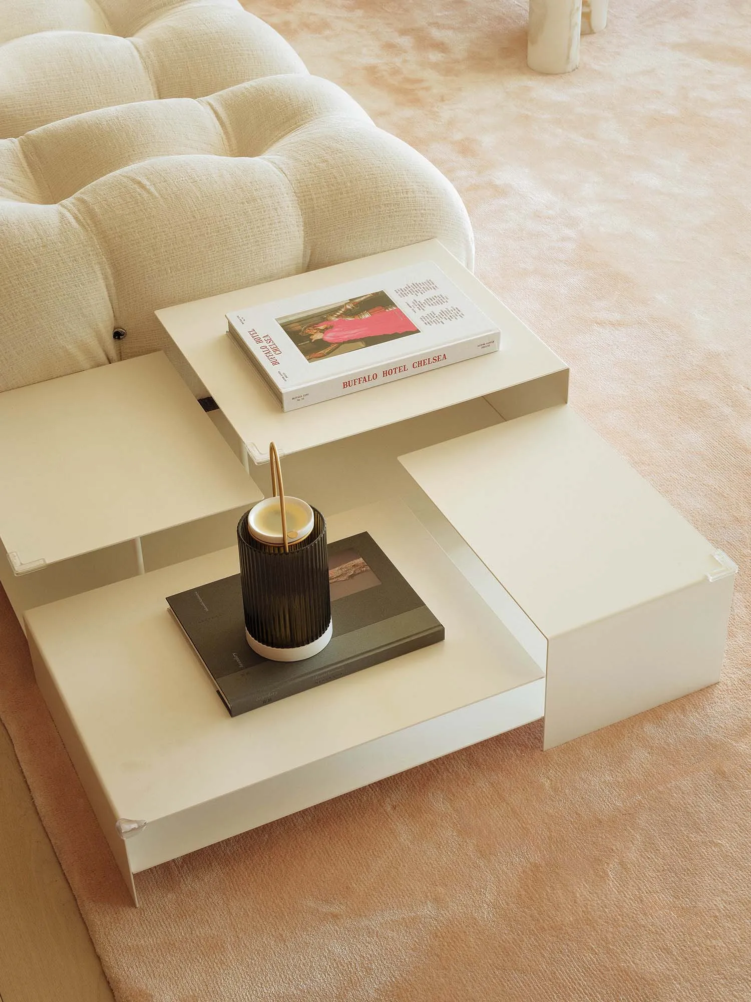 Cozy living space with a white couch on a carpeted floor, featuring a coffee table with books and a magazine