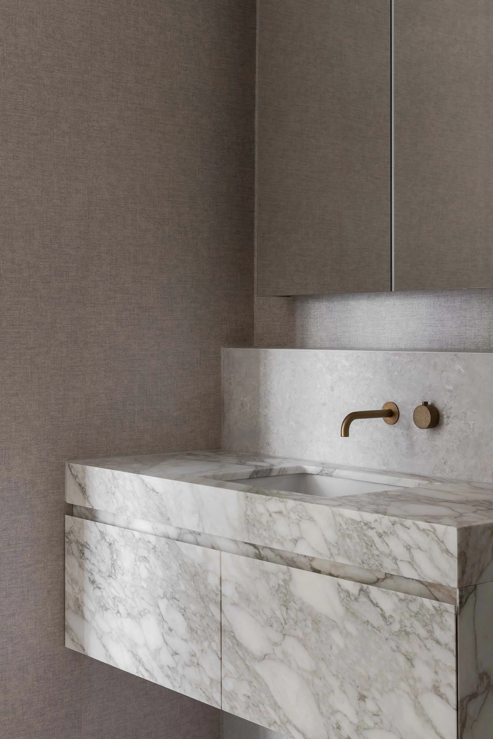 Modern bathroom with a marble countertop, sink, mirror, and cabinet, featuring a well-lit and elegant design