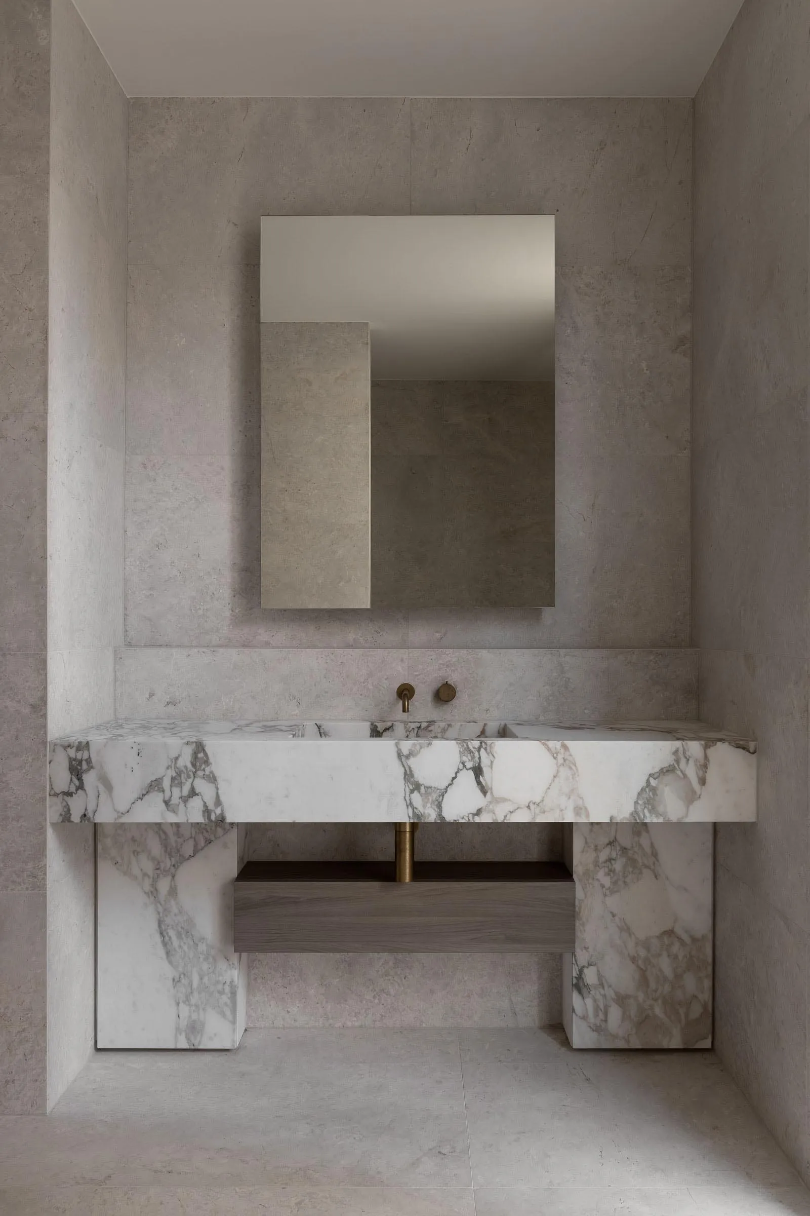 Bathroom with a marble sink area, mirror, and two faucets, giving off an elegant and luxurious vibe