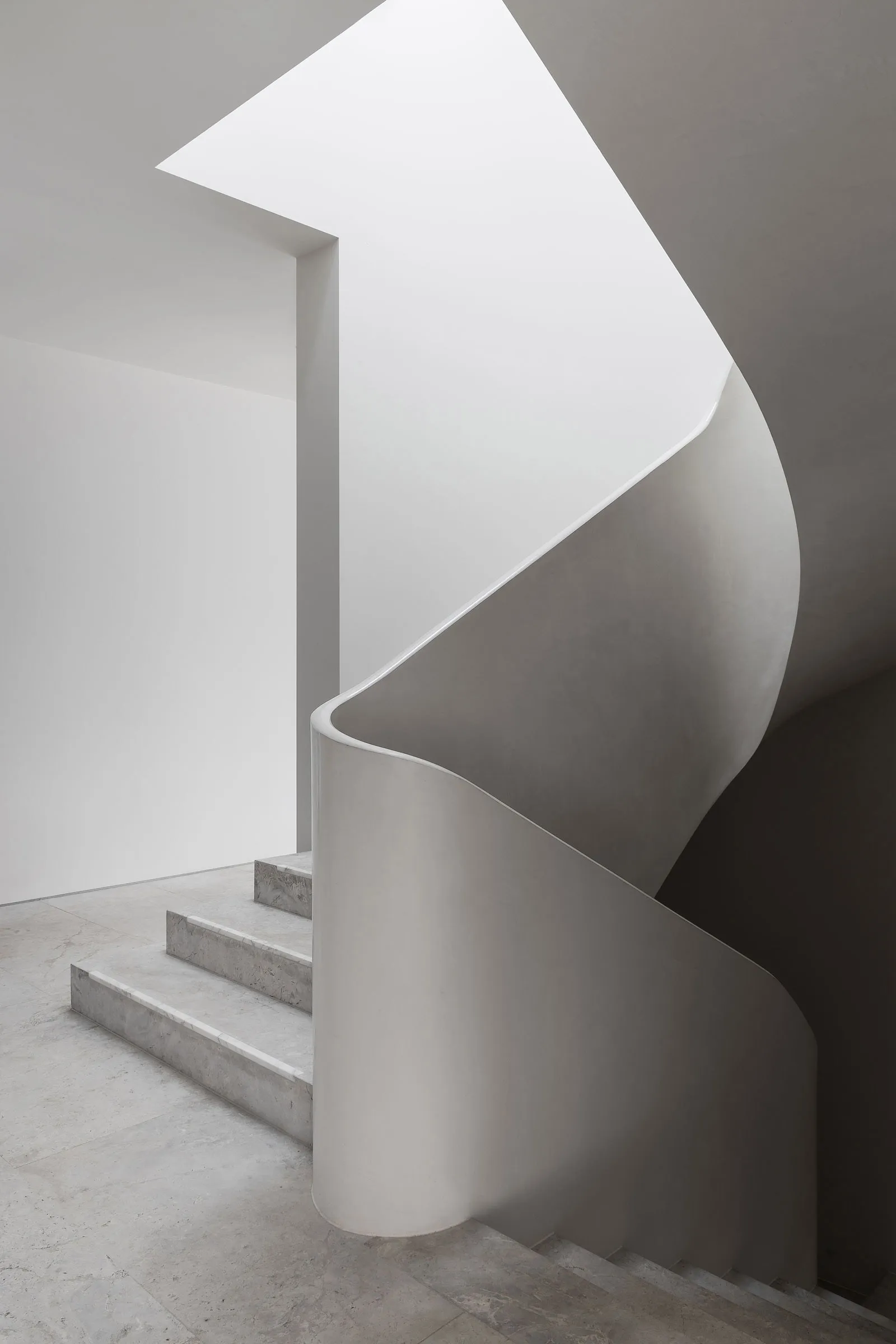 A gray concrete staircase with three steps leading upwards in a residential home, creating a sense of depth and structure