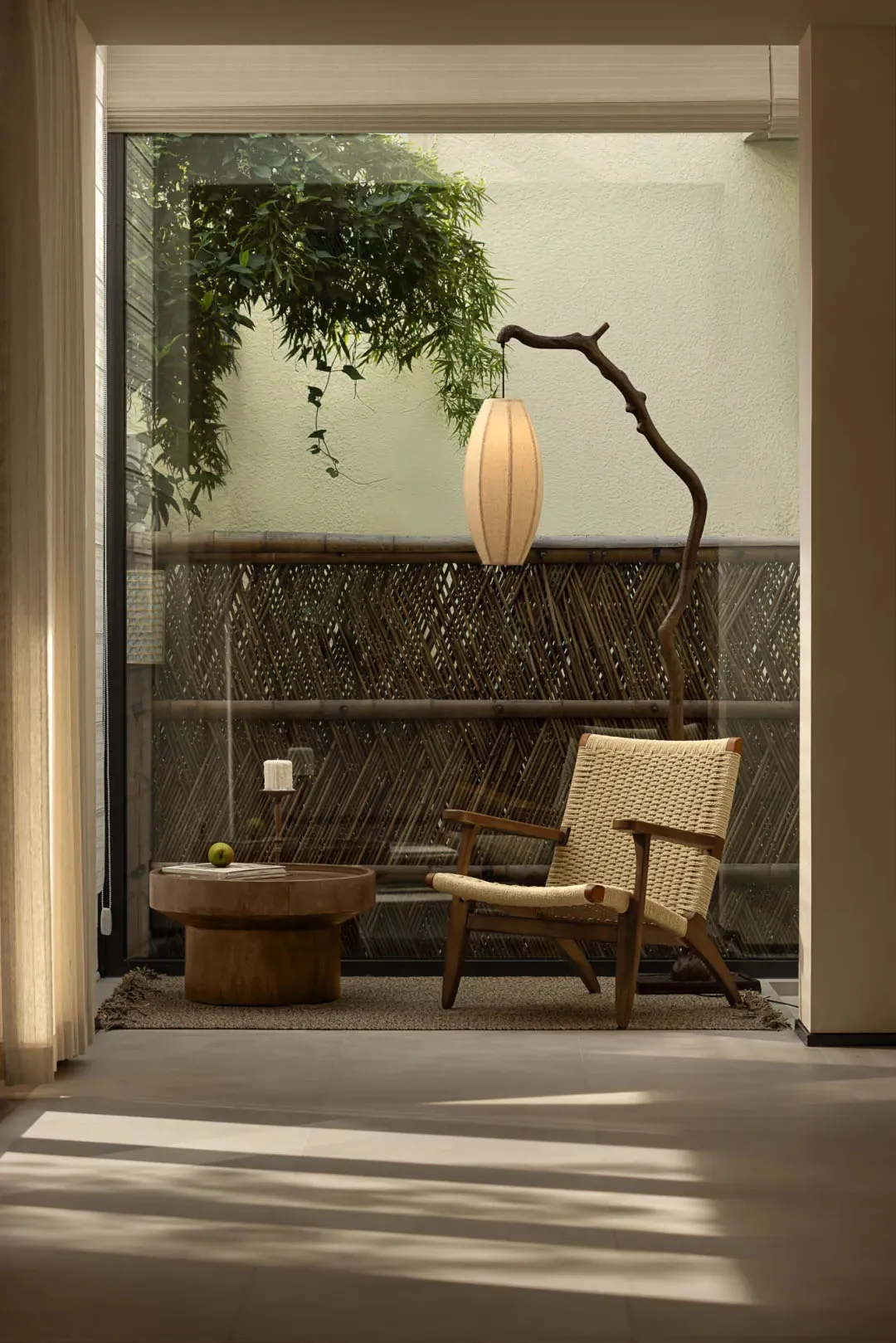 Cozy living space with a wooden chair, rug, dining table, and potted plant, creating a warm and inviting atmosphere