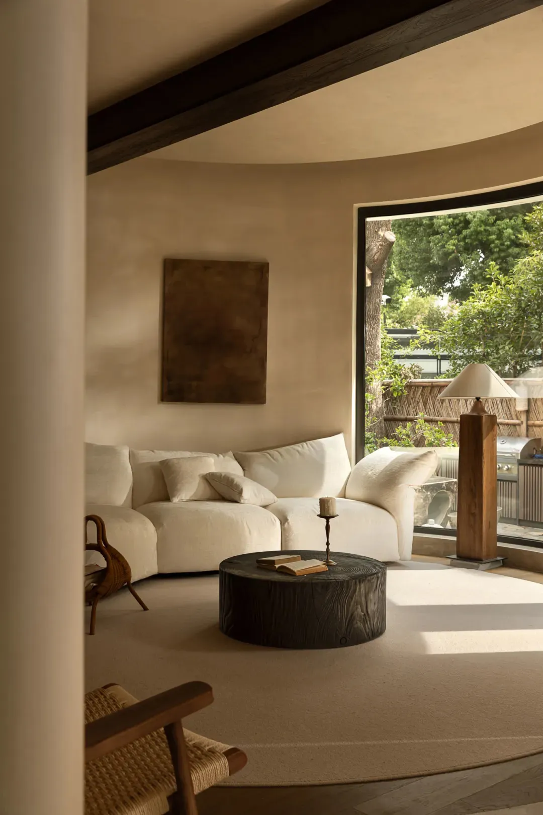 Bright and inviting living area with a white couch, two chairs, a dining table, and a book on the couch, surrounded by sunlight streaming through the window