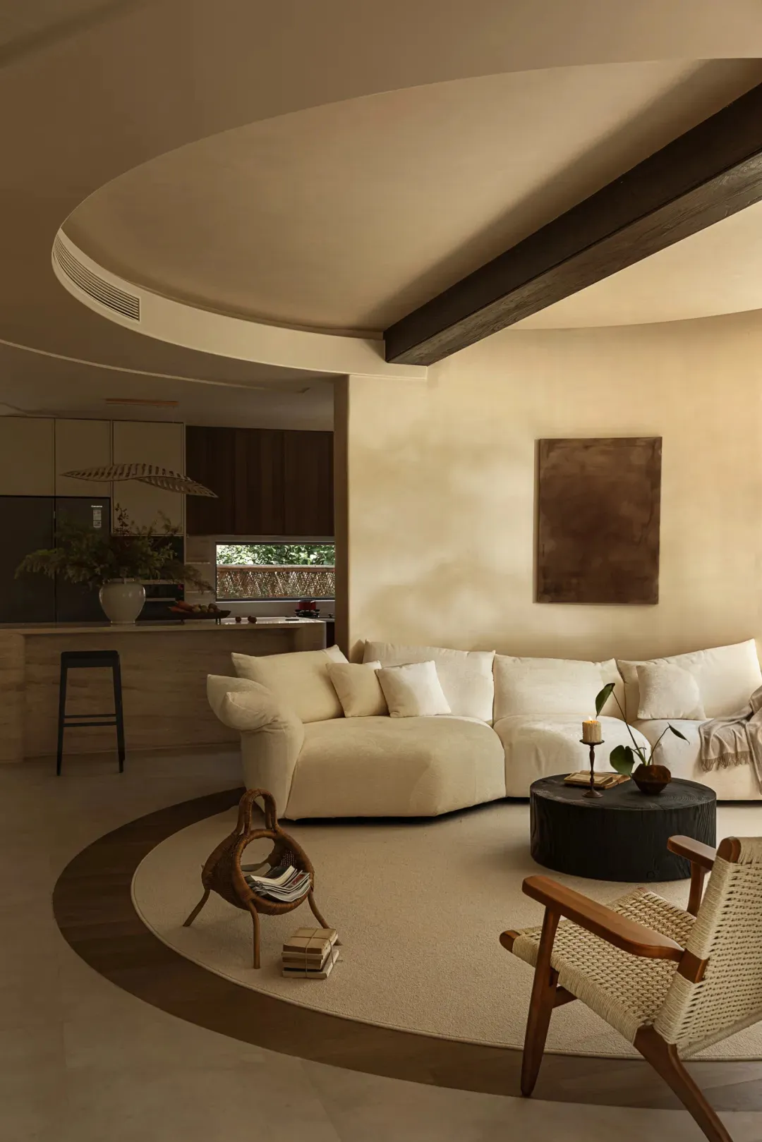 Open living area with white walls, beige furniture, and decorative elements, featuring a kitchen, dining area, and living room