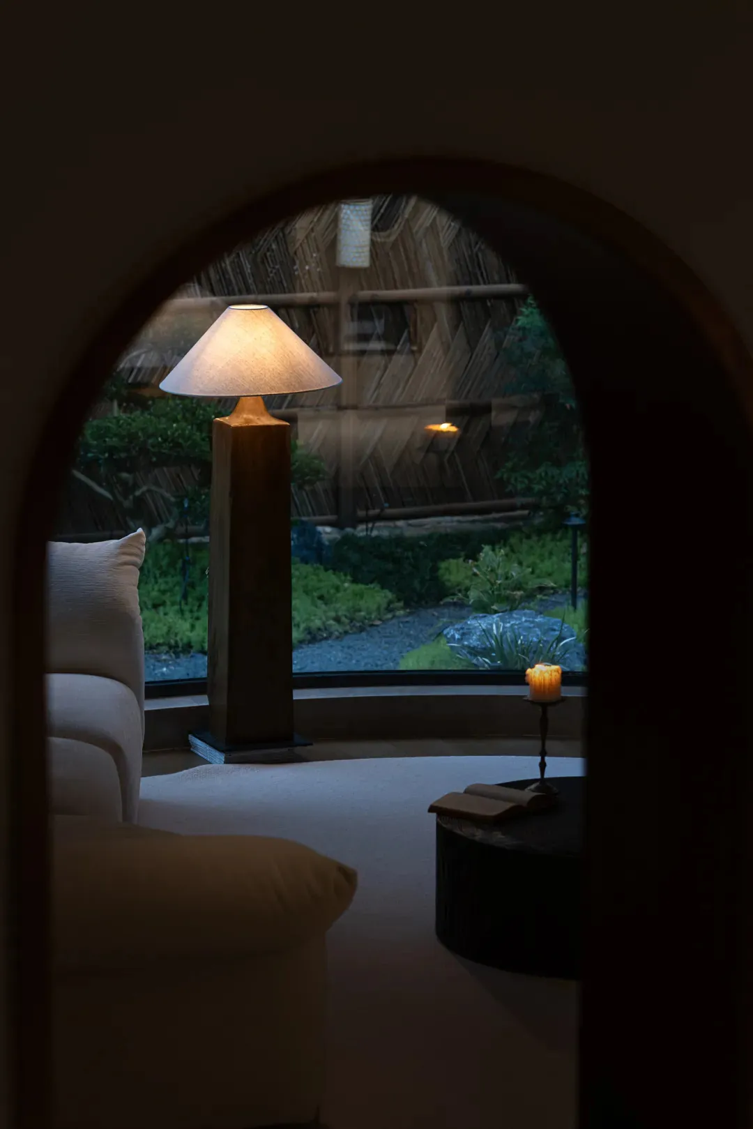 Cozy living space with a couch, two chairs, and a lamp, illuminated by natural light from a window