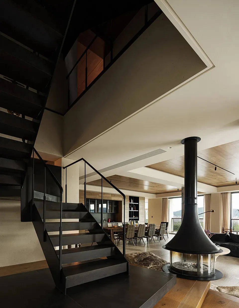 Warm and inviting living room with a large fireplace, chairs, and a dining table, surrounded by cozy atmosphere