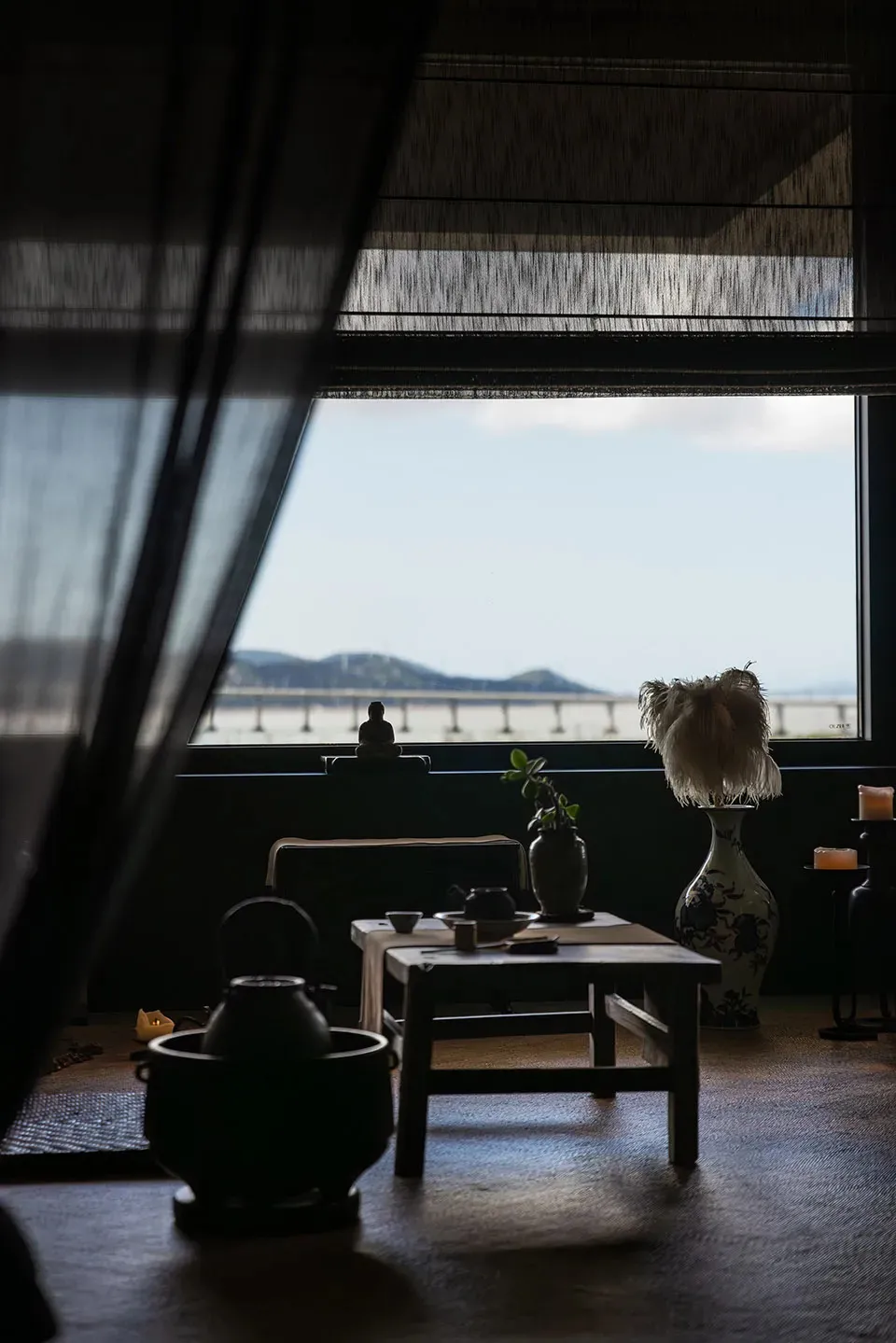 Cozy dining space with a table, chairs, couch, and ocean view, decorated with vases, plants, and a bowl, providing a relaxing atmosphere
