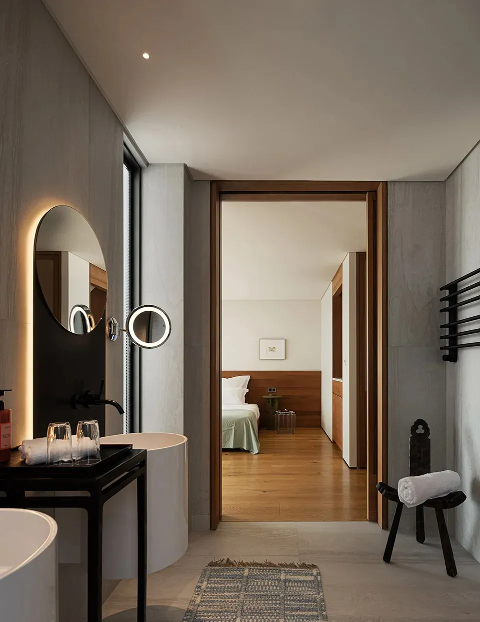 Well-lit bedroom with wooden floors and walls, featuring a large mirror, two beds, and a chair, creating a cozy and inviting atmosphere