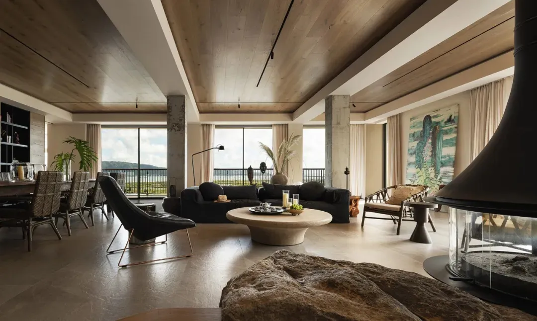 Open living area with a black couch near a window, a dining table, kitchenette, and various decorative items