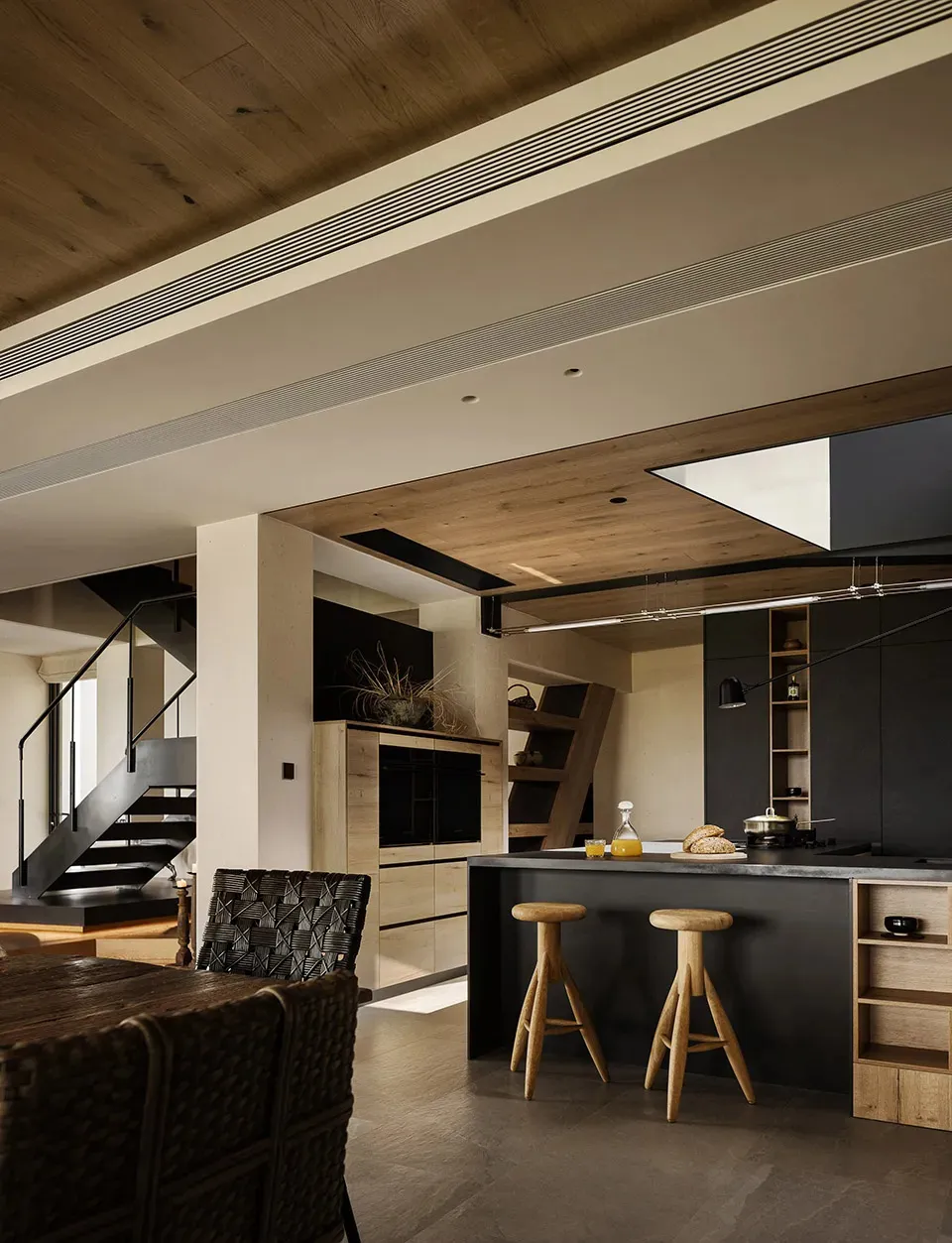 Open living area with wooden floors and walls, featuring a couch, chairs, vases, and a potted plant, with a warm and inviting atmosphere