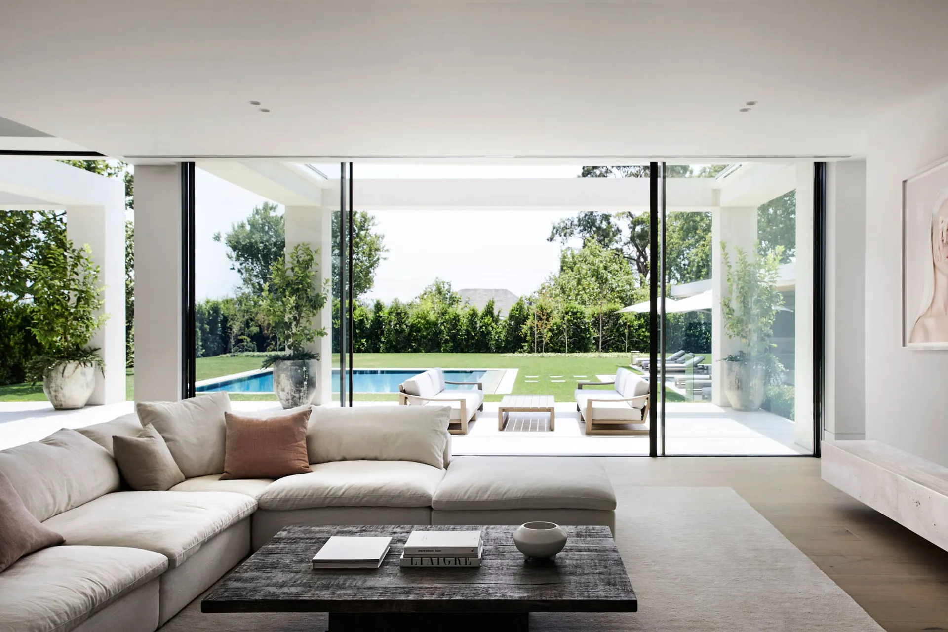 An inviting open living area with a white couch, chairs, a dining table, and decorative items, lit by natural sunlight through glass doors