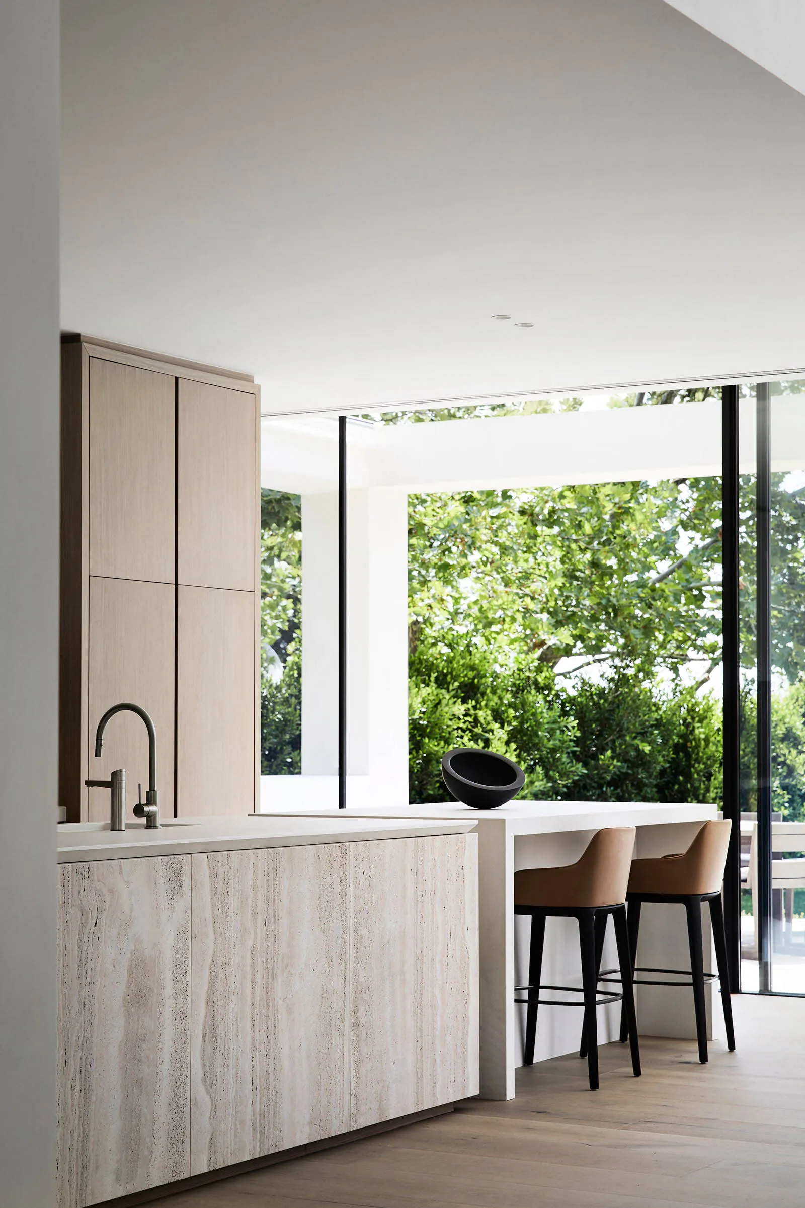 Modern kitchen and dining area with white cabinets, a sink, table, chairs, and potted plants