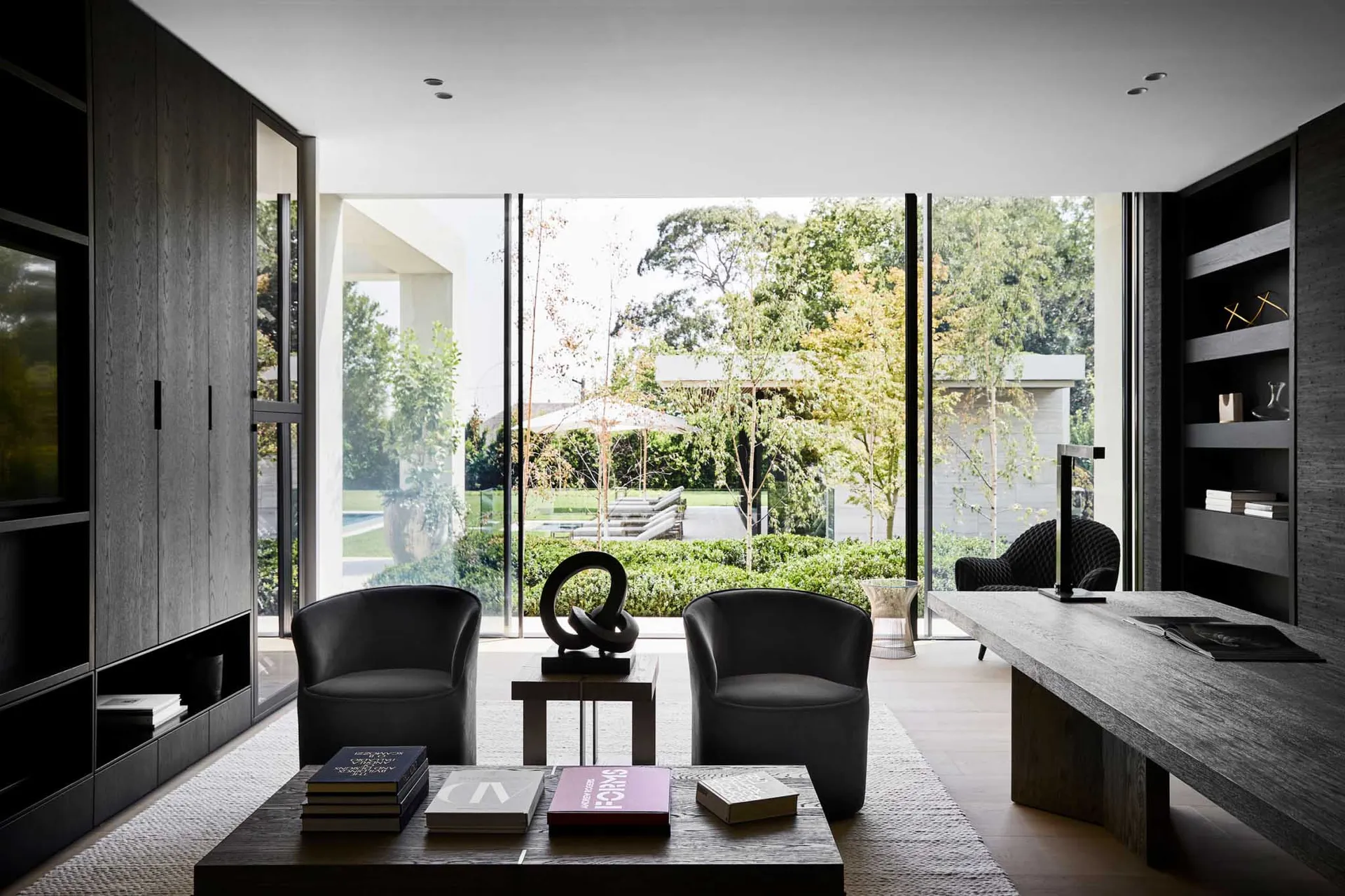 A modern living room with two chairs, a coffee table, and several books, featuring a well-lit and inviting atmosphere