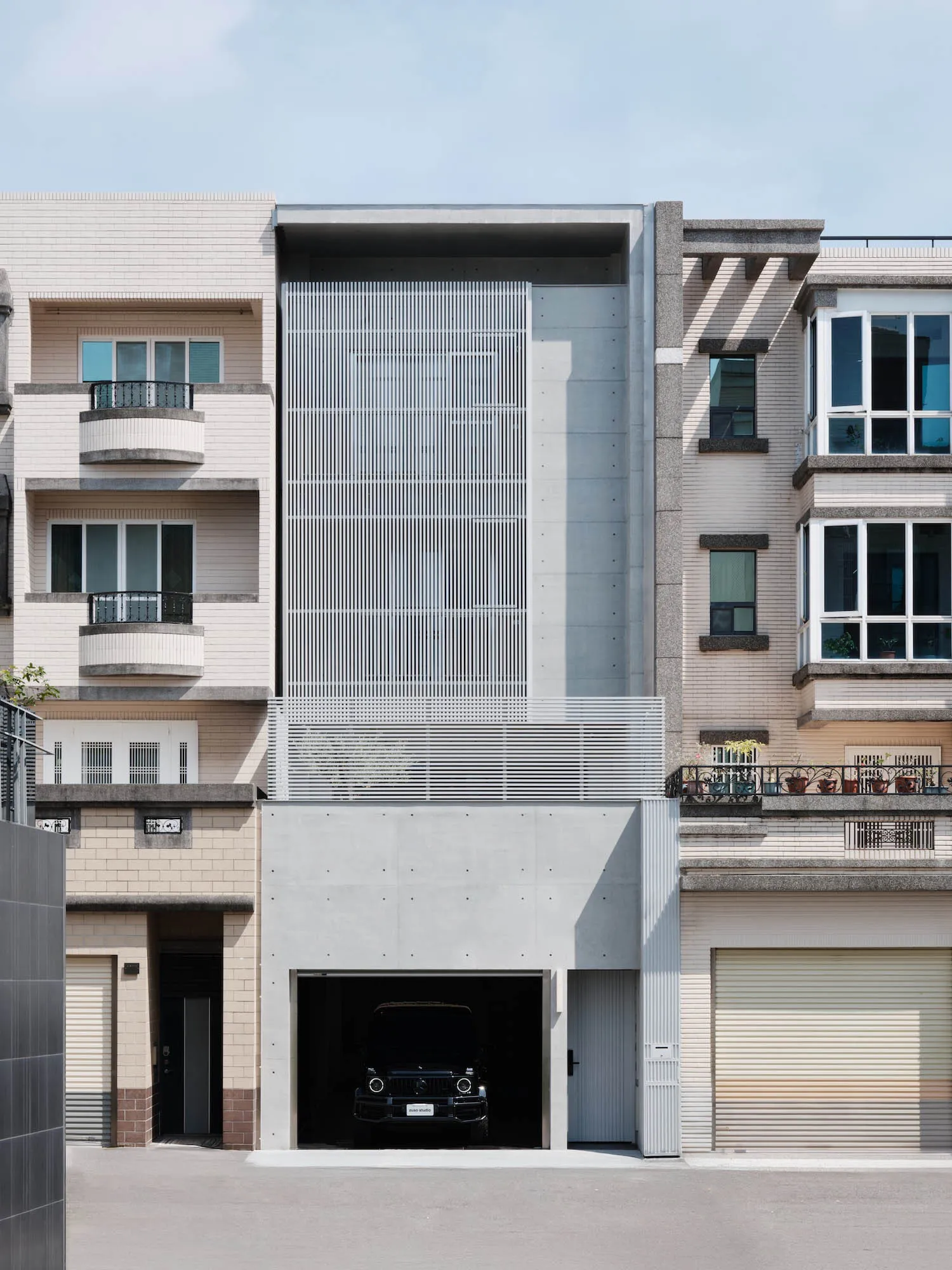 A modern building with a prominent glass wall, surrounded by windows and balconies, set against a city backdrop