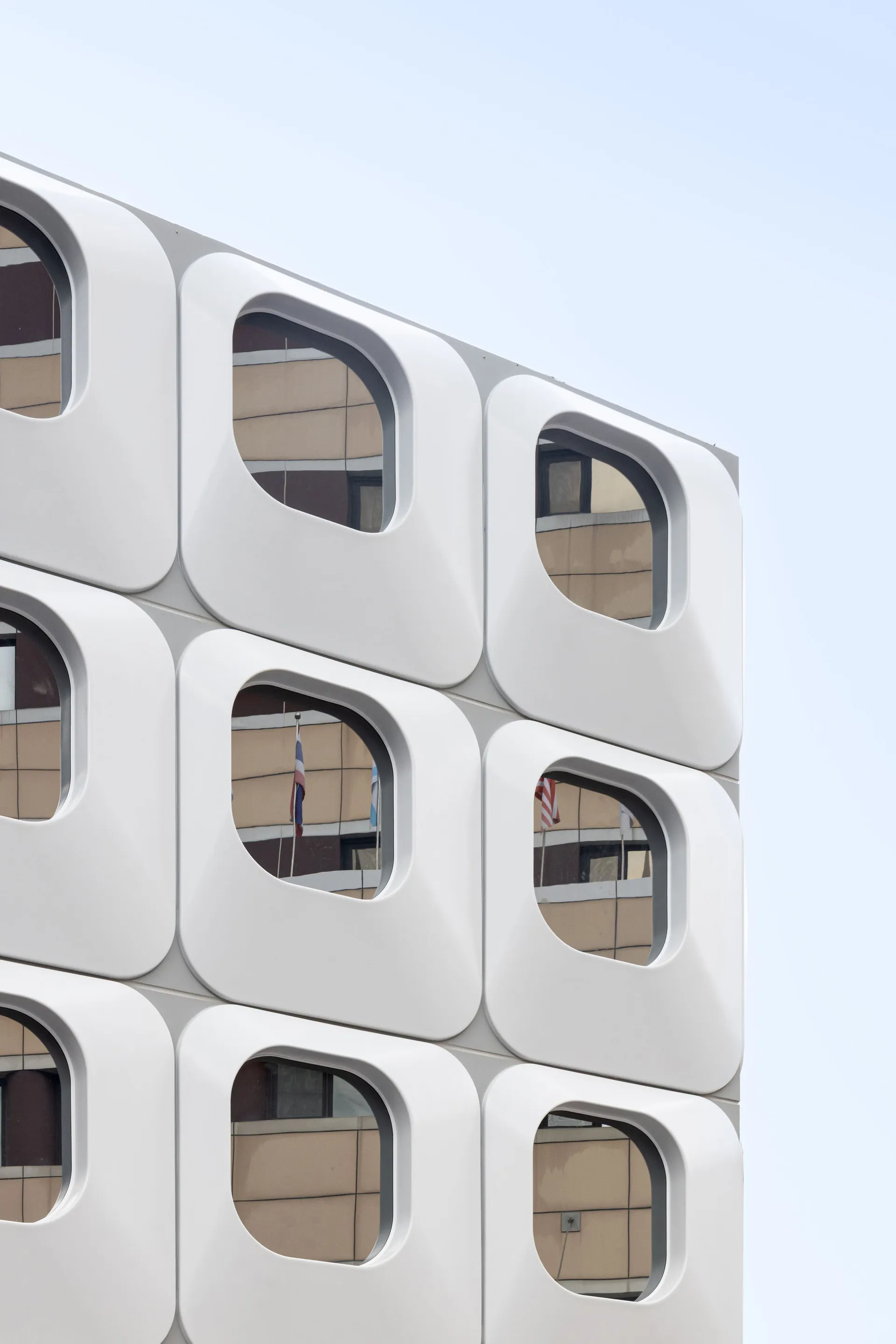 A large white building with a modern design, featuring a grid pattern of square windows and a predominantly white facade