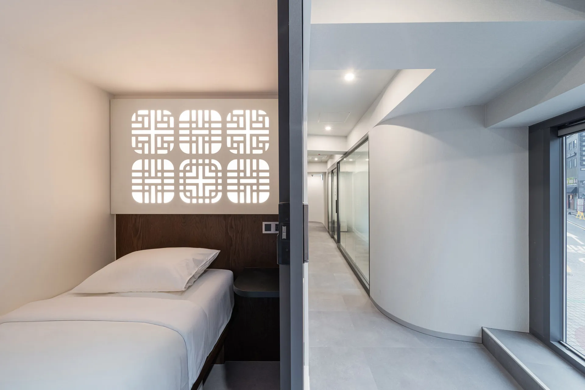 A modern bedroom with a bed, closet, and door, decorated with patterned wallpaper and a wooden headboard, in a well-lit space
