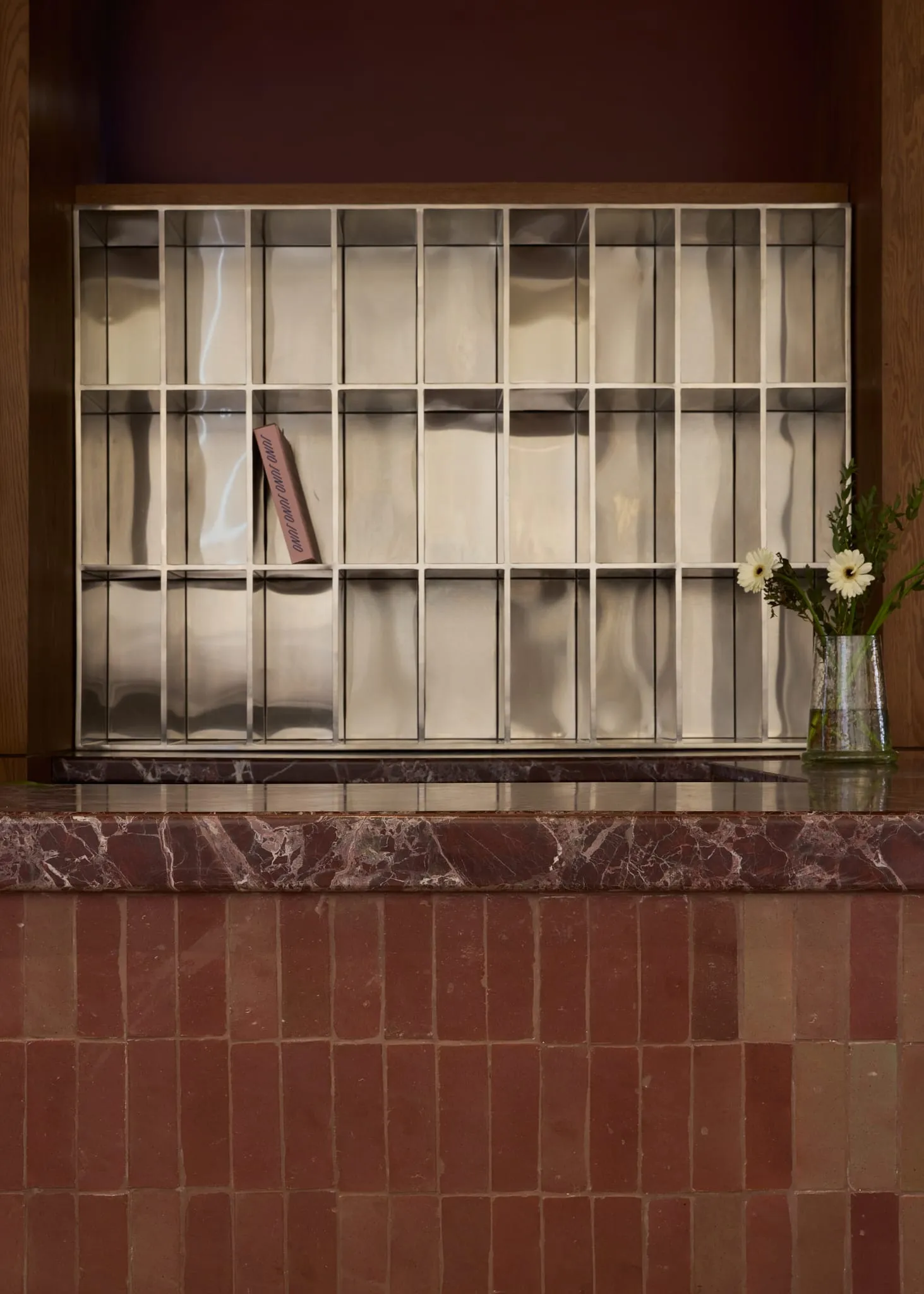 A marble countertop with a pink paperback book placed on it, set in a room with a wooden countertop and an elegant atmosphere